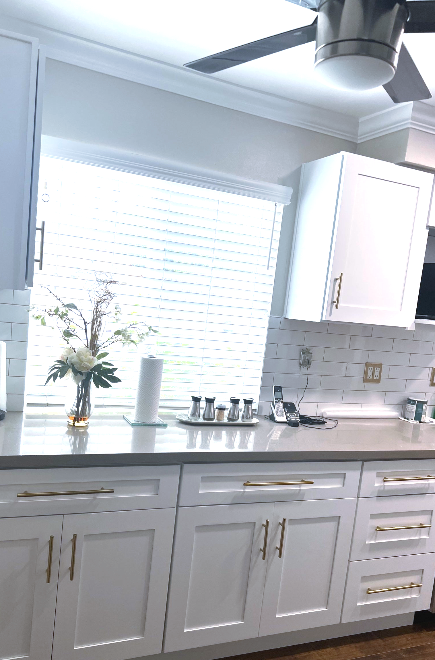 A kitchen with white cabinets and a ceiling fan