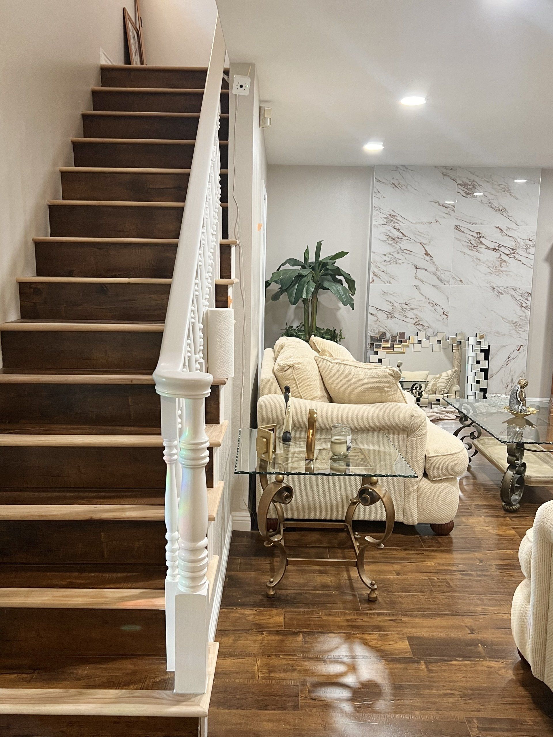 A living room with stairs leading up to the second floor and a couch.