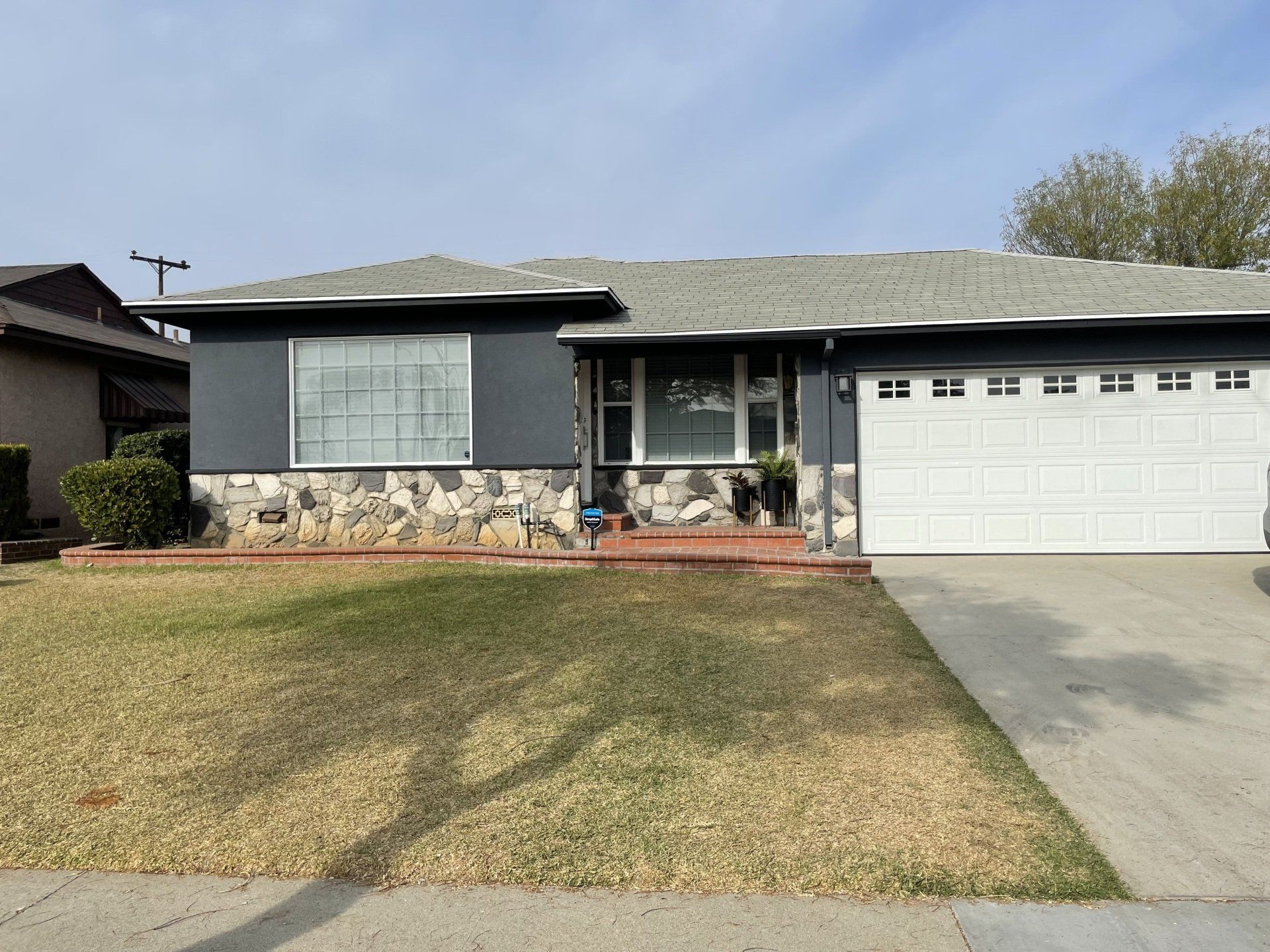 A house with a garage door and a large lawn in front of it.