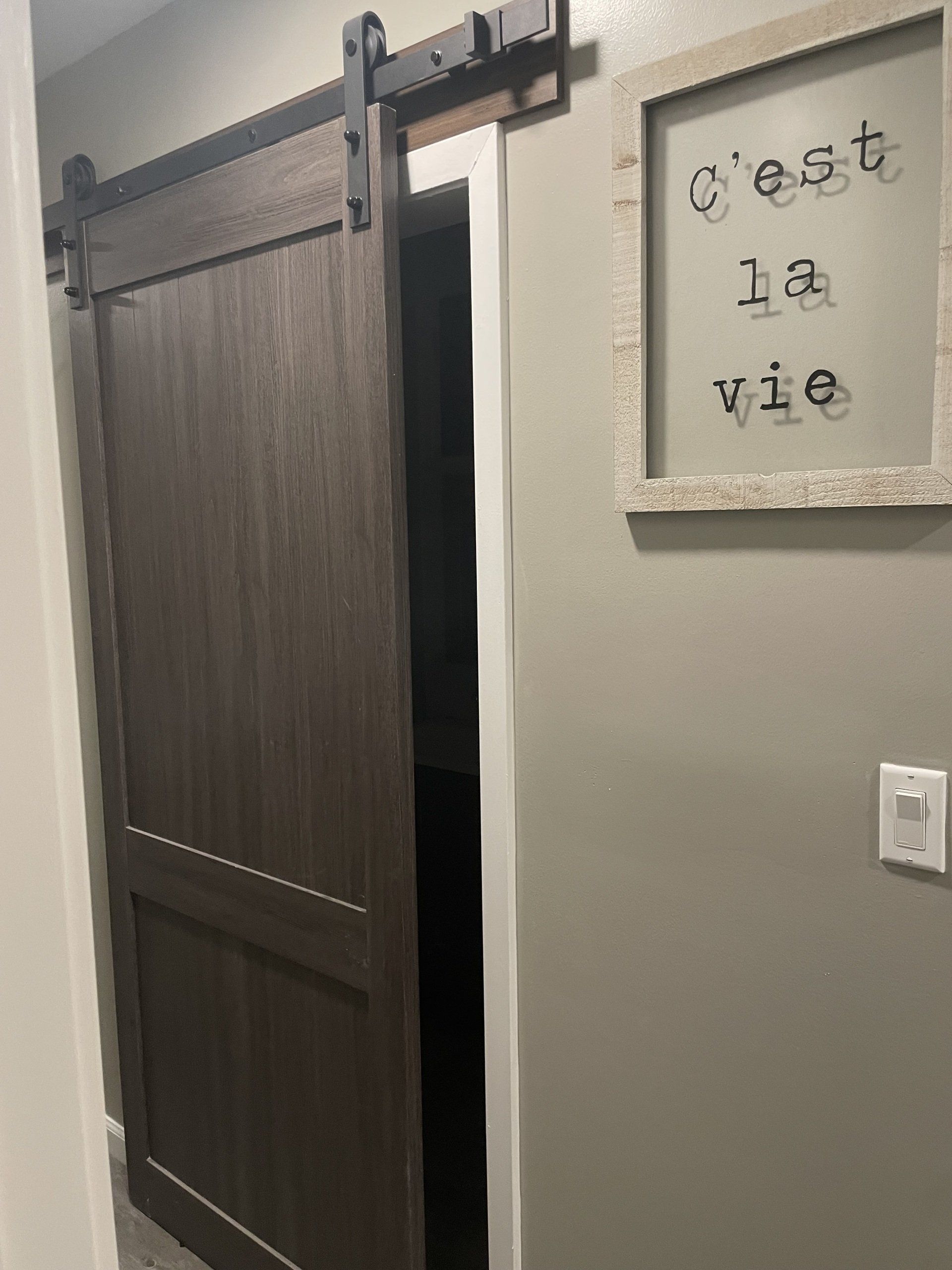 A sliding barn door with a sign on the wall above it.