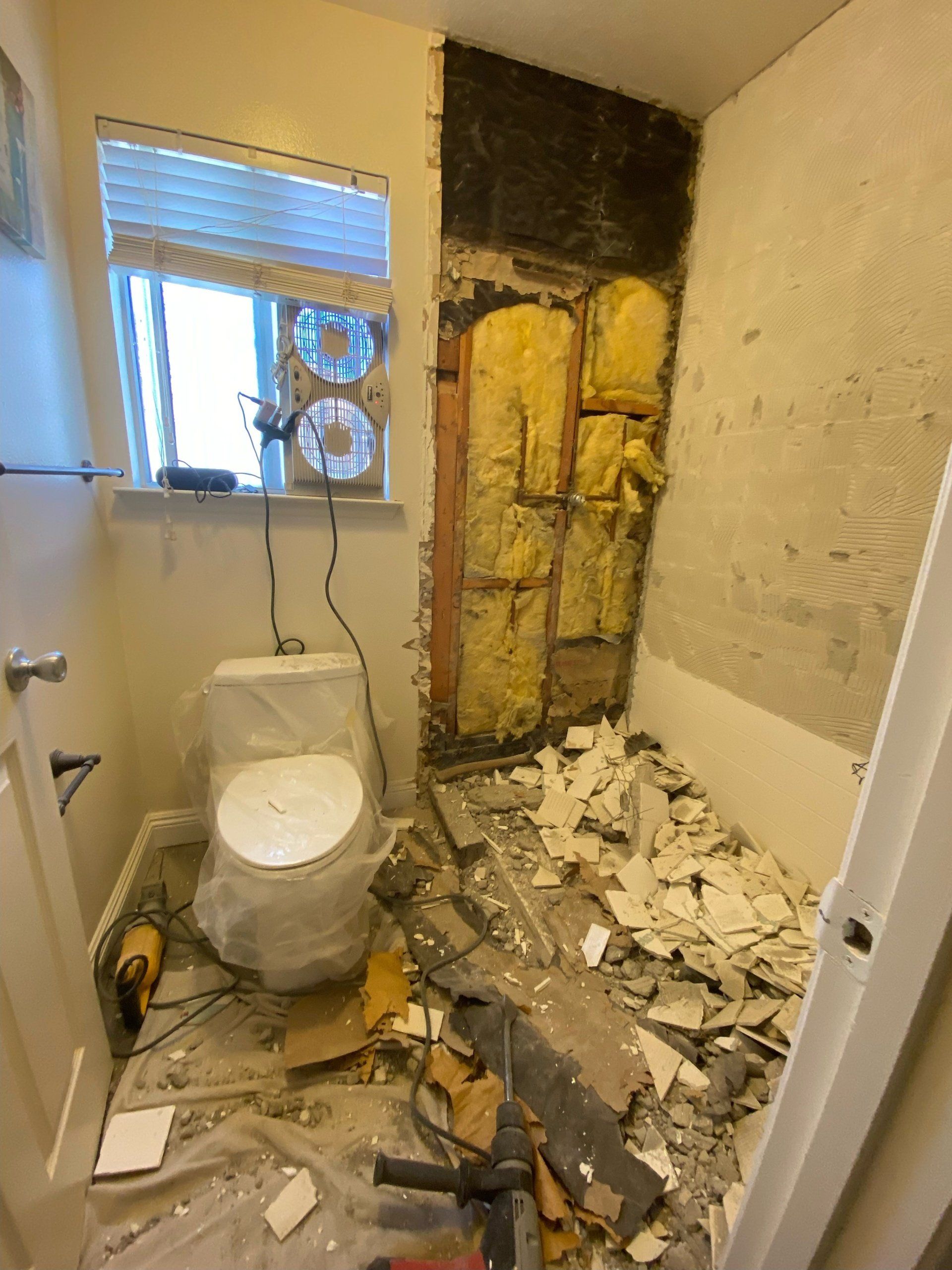 A bathroom under construction with a toilet and a window.