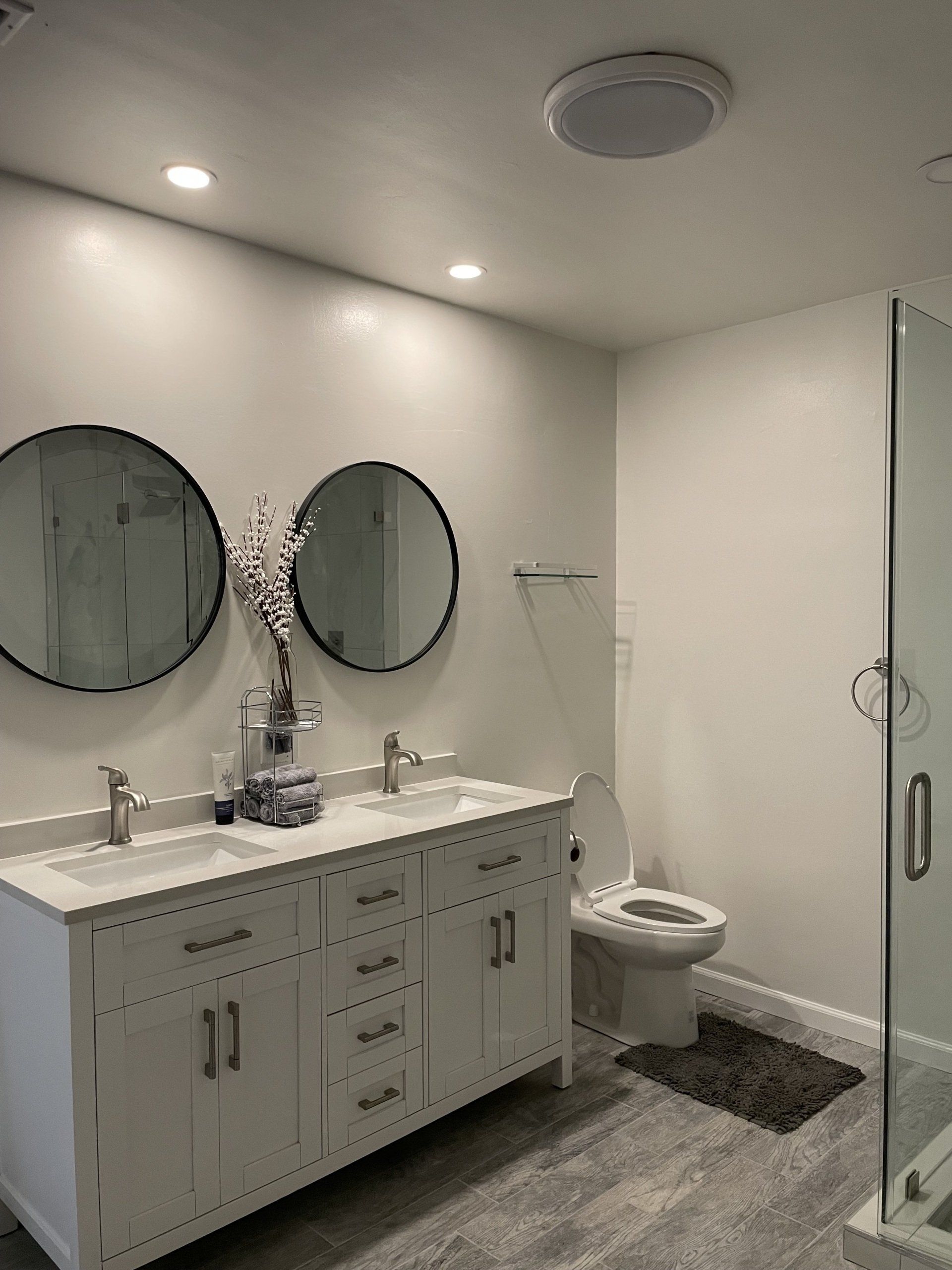 A bathroom with two sinks , a toilet , and a walk in shower.