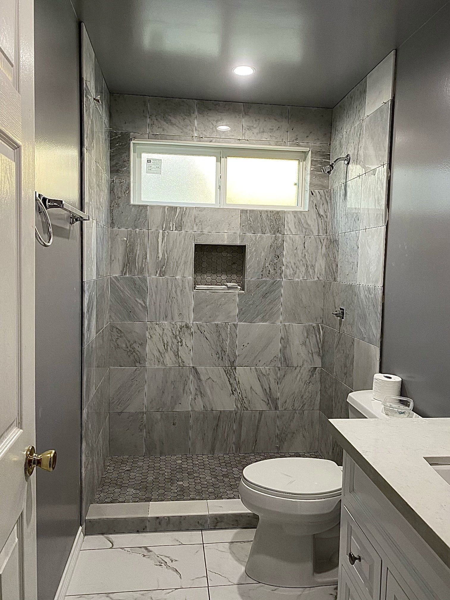 A bathroom with a toilet , sink , shower and window.