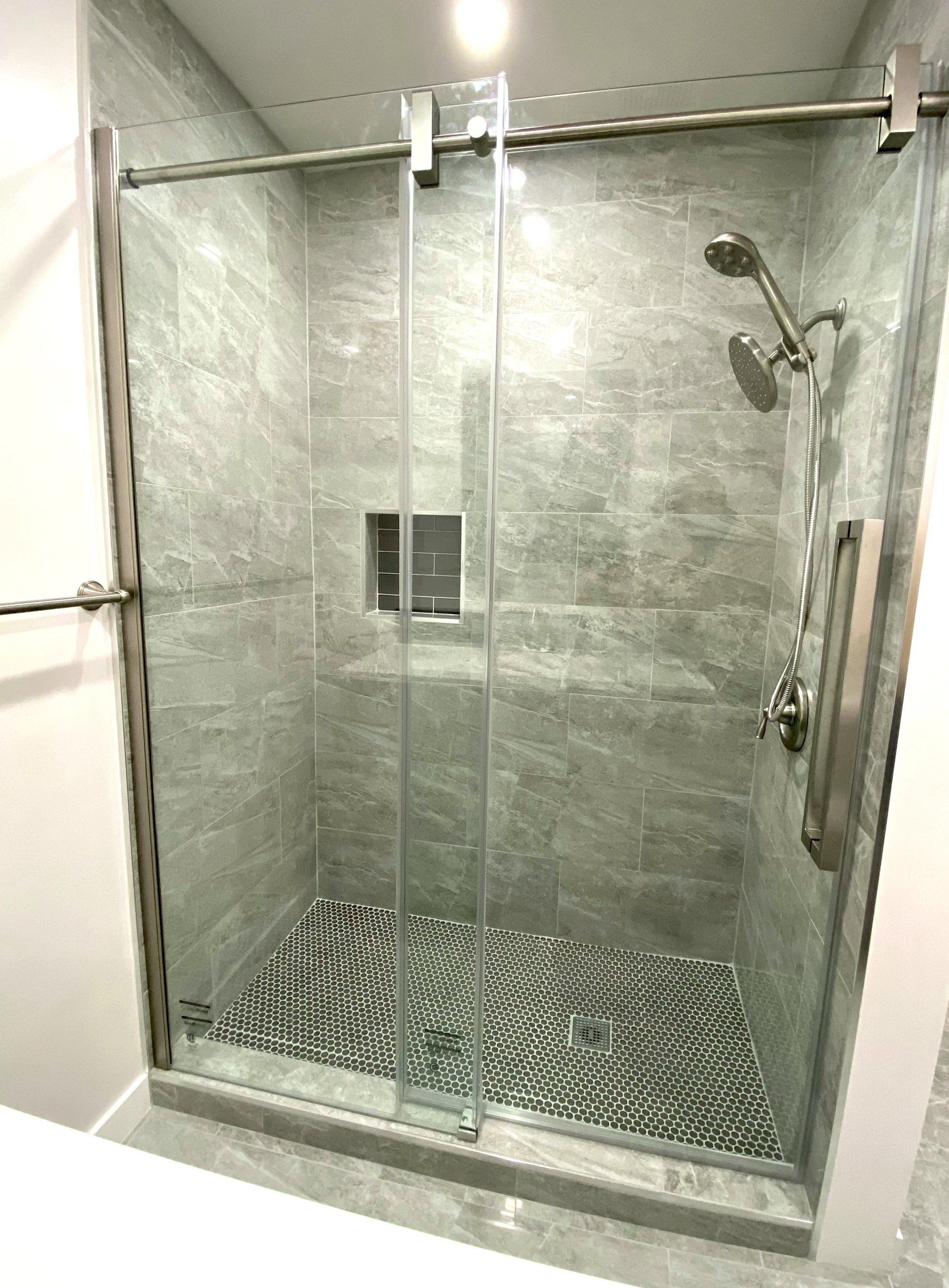 A bathroom with a walk in shower with a sliding glass door.