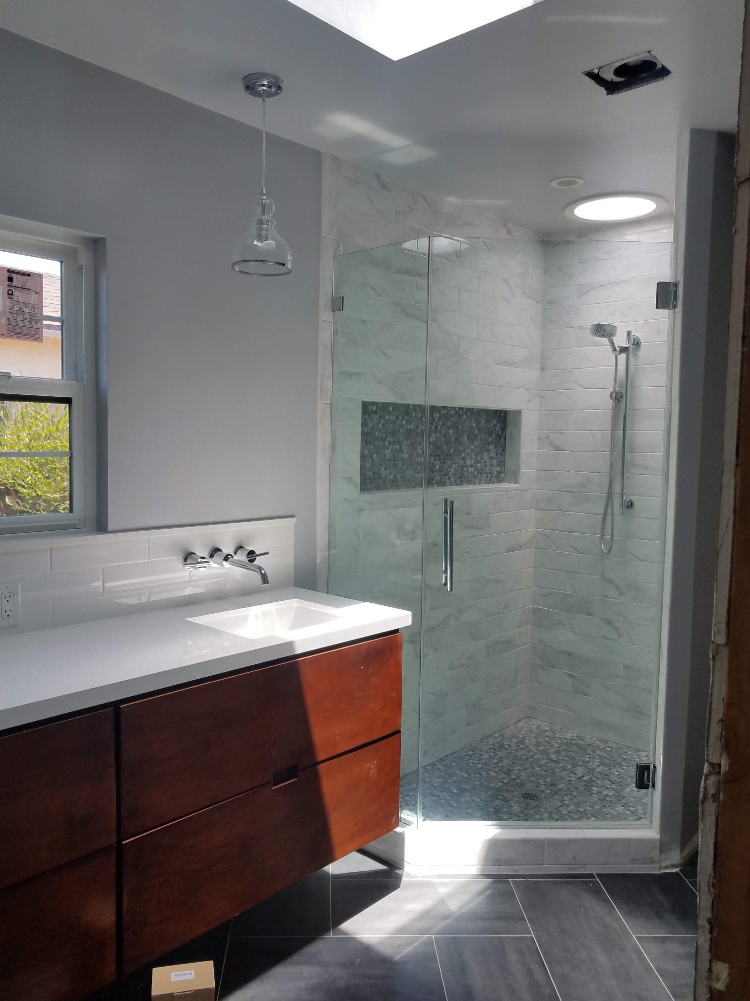 A bathroom with a walk in shower and a sink