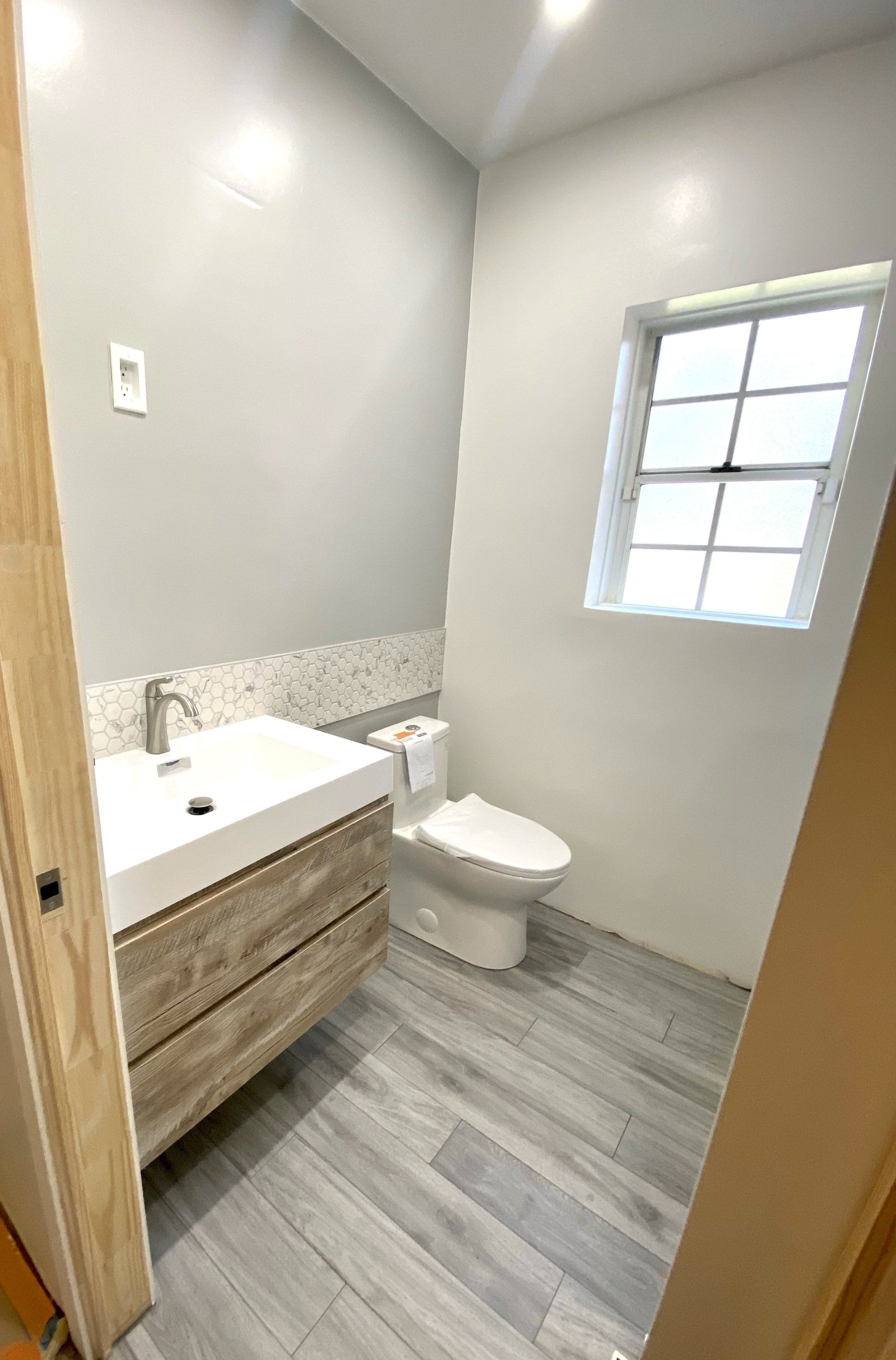 A bathroom with a sink , toilet and window.