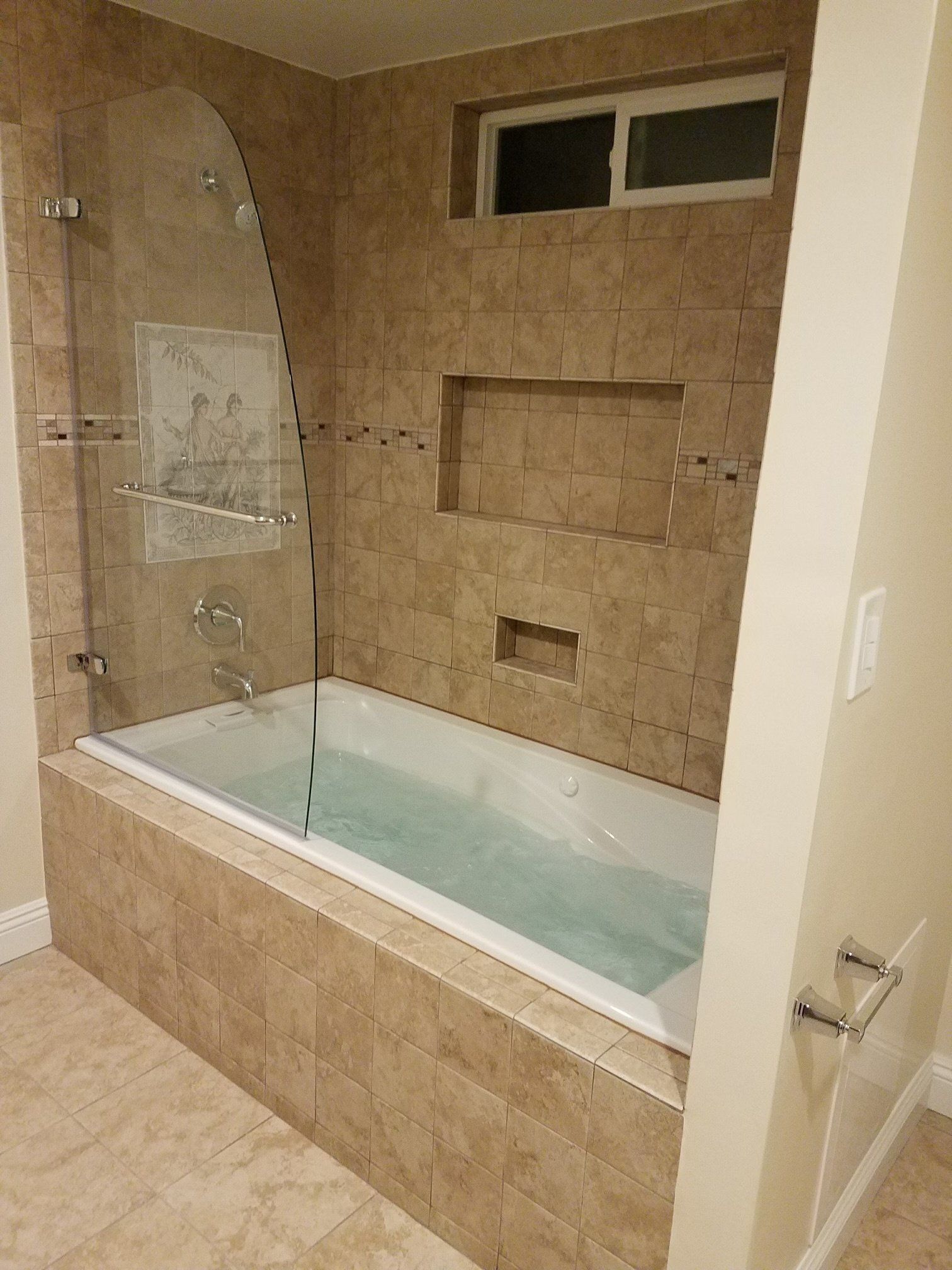 A bathtub in a bathroom with a glass shower door.