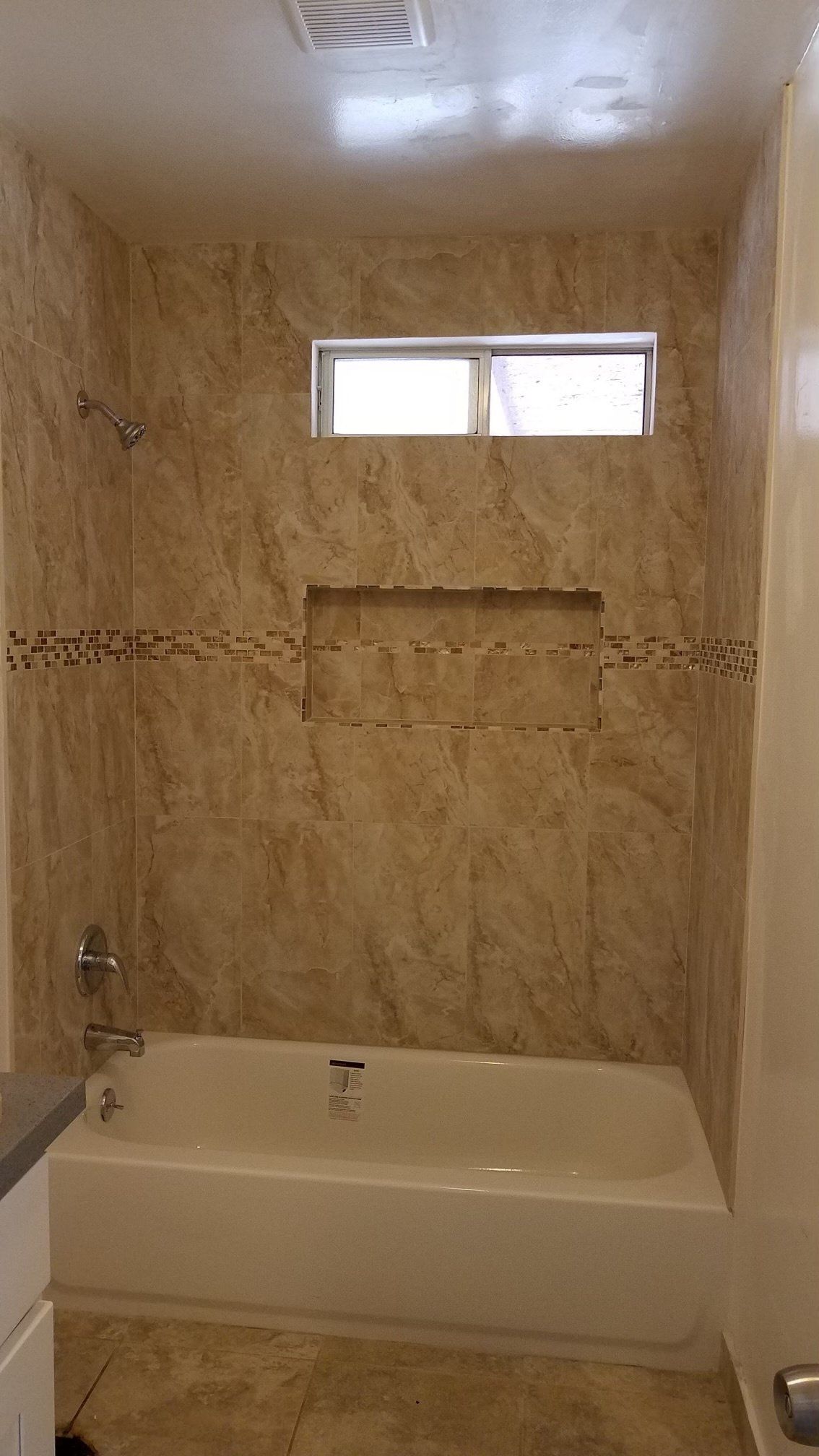 A bathroom with a tub , shower , and window.