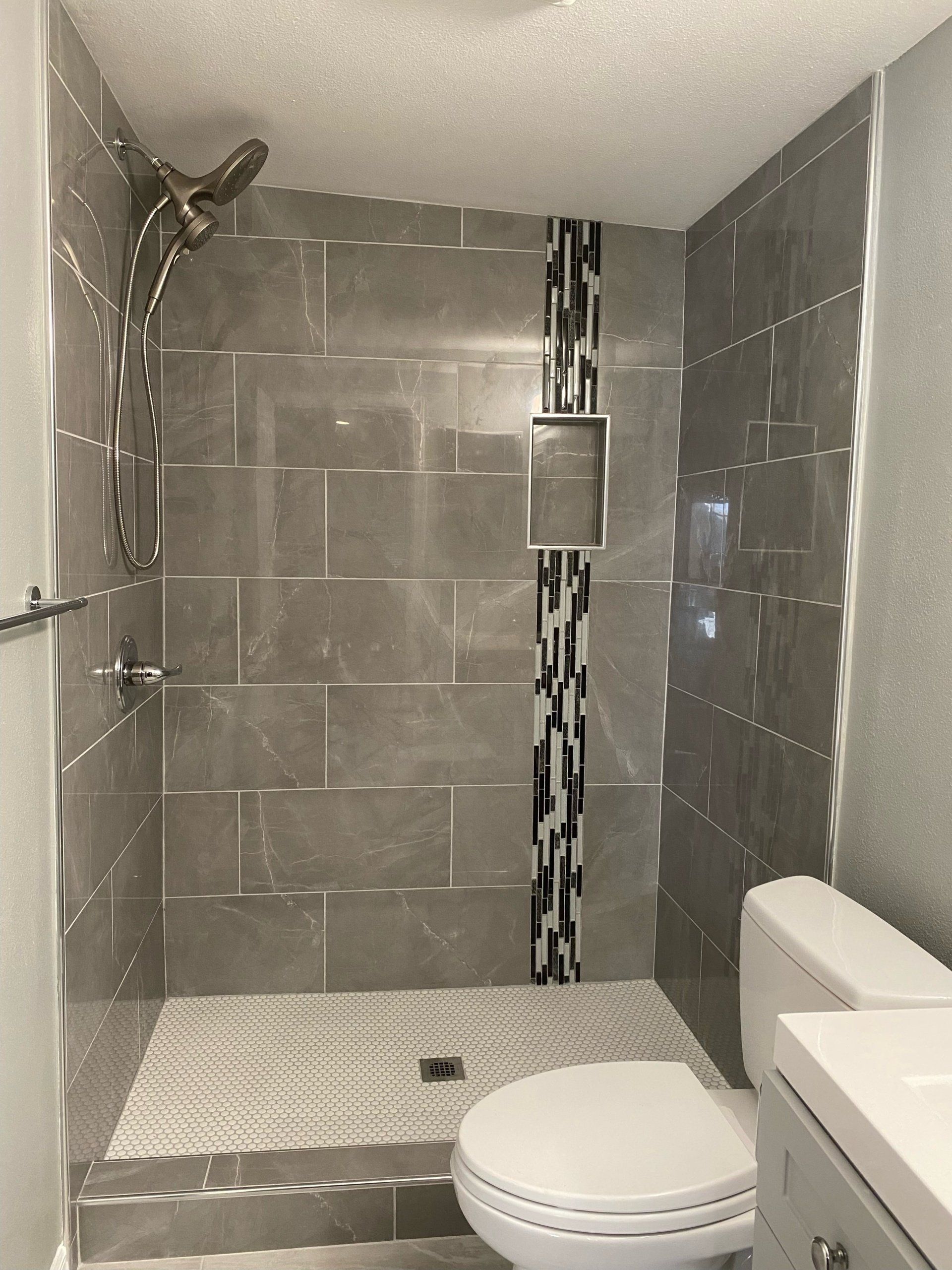 A bathroom with a toilet , sink and shower.