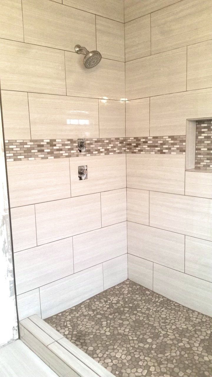 A bathroom with white tiles and a walk in shower.