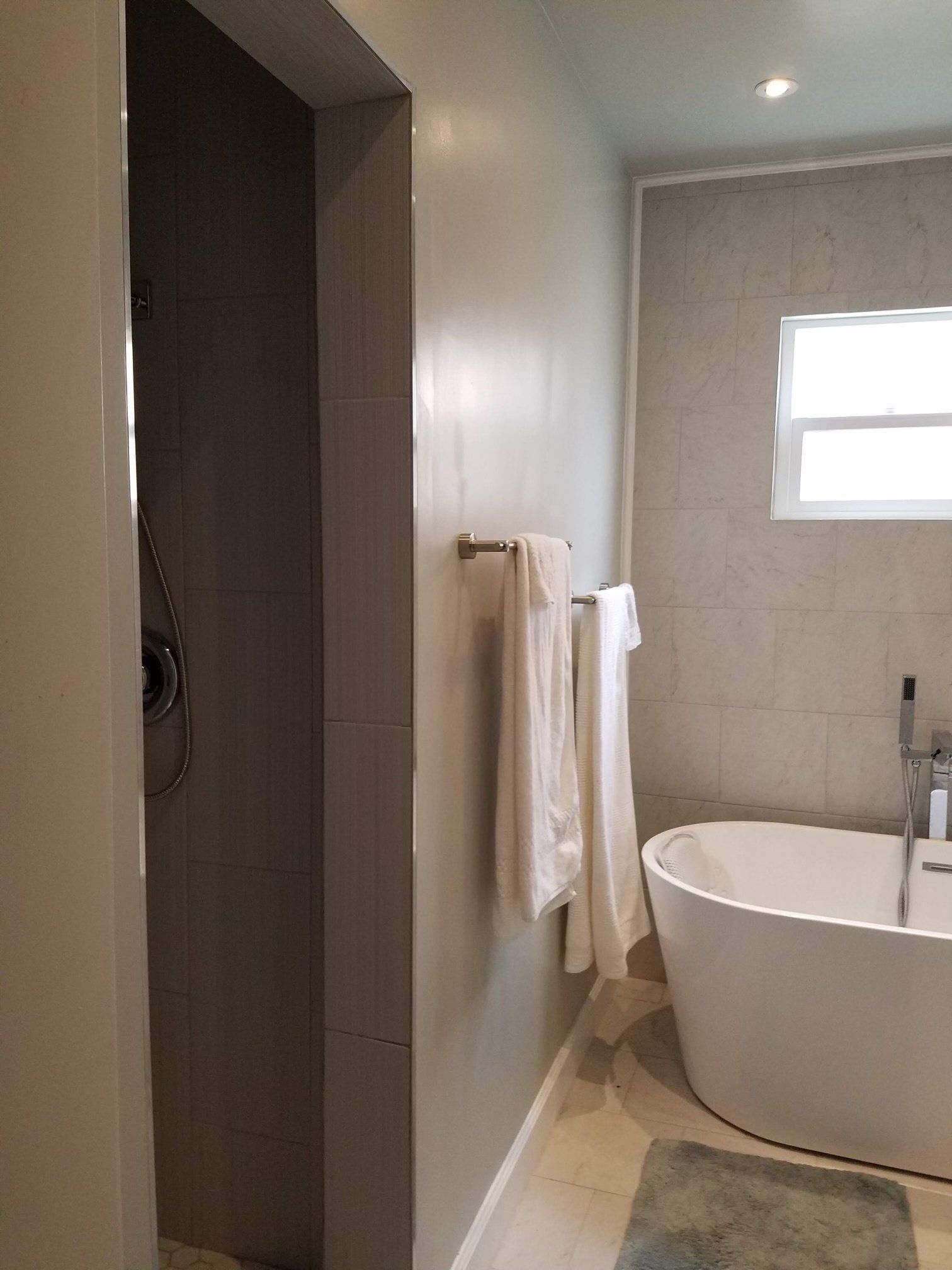 A bathroom with a tub , shower , and window.