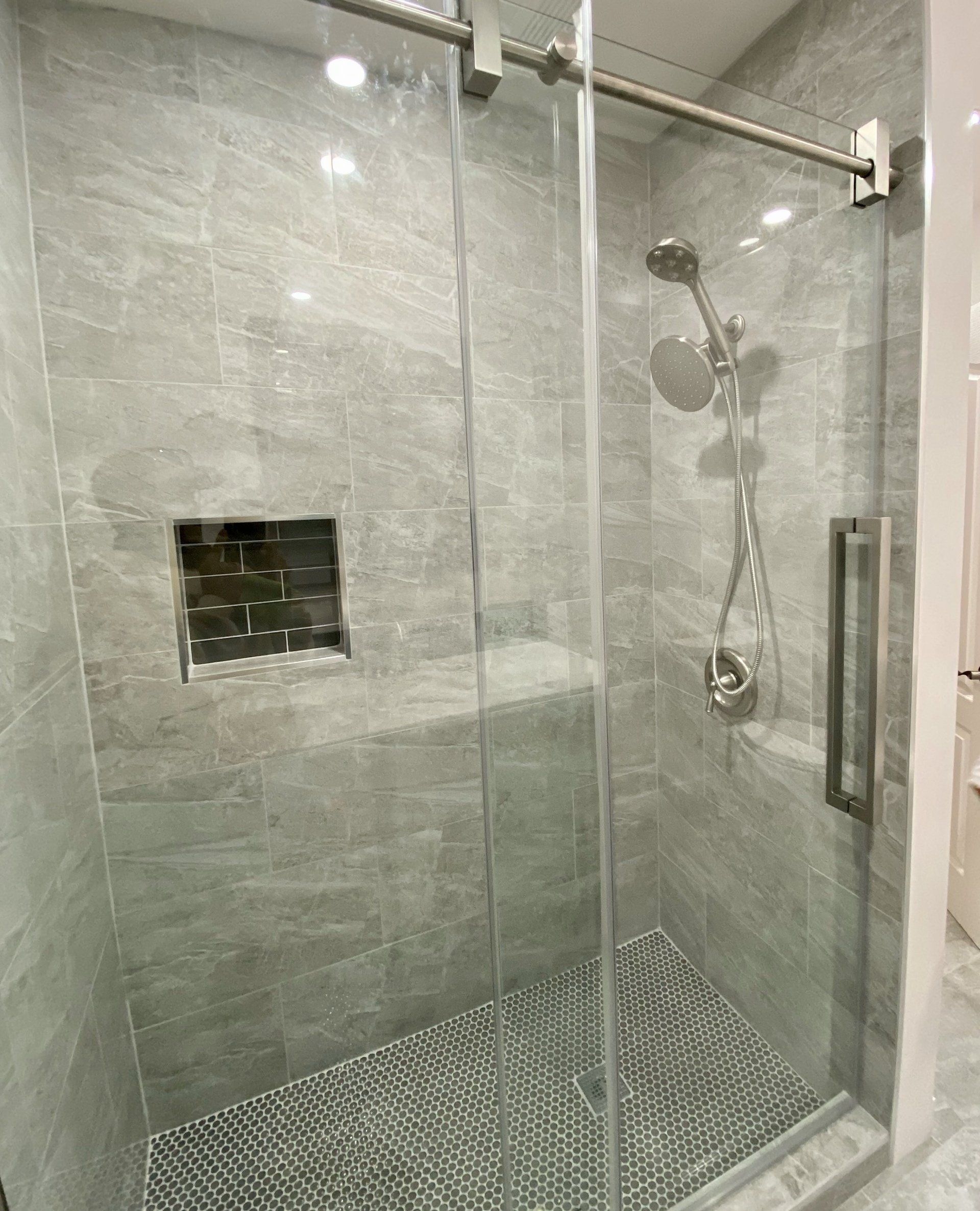 A shower with a sliding glass door and a shower head.