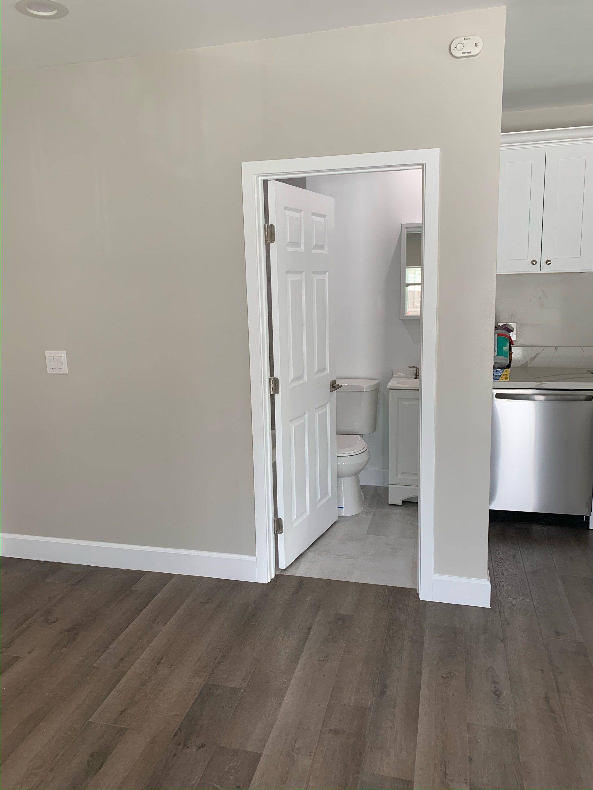 A bathroom with a toilet , sink and dishwasher in a house.