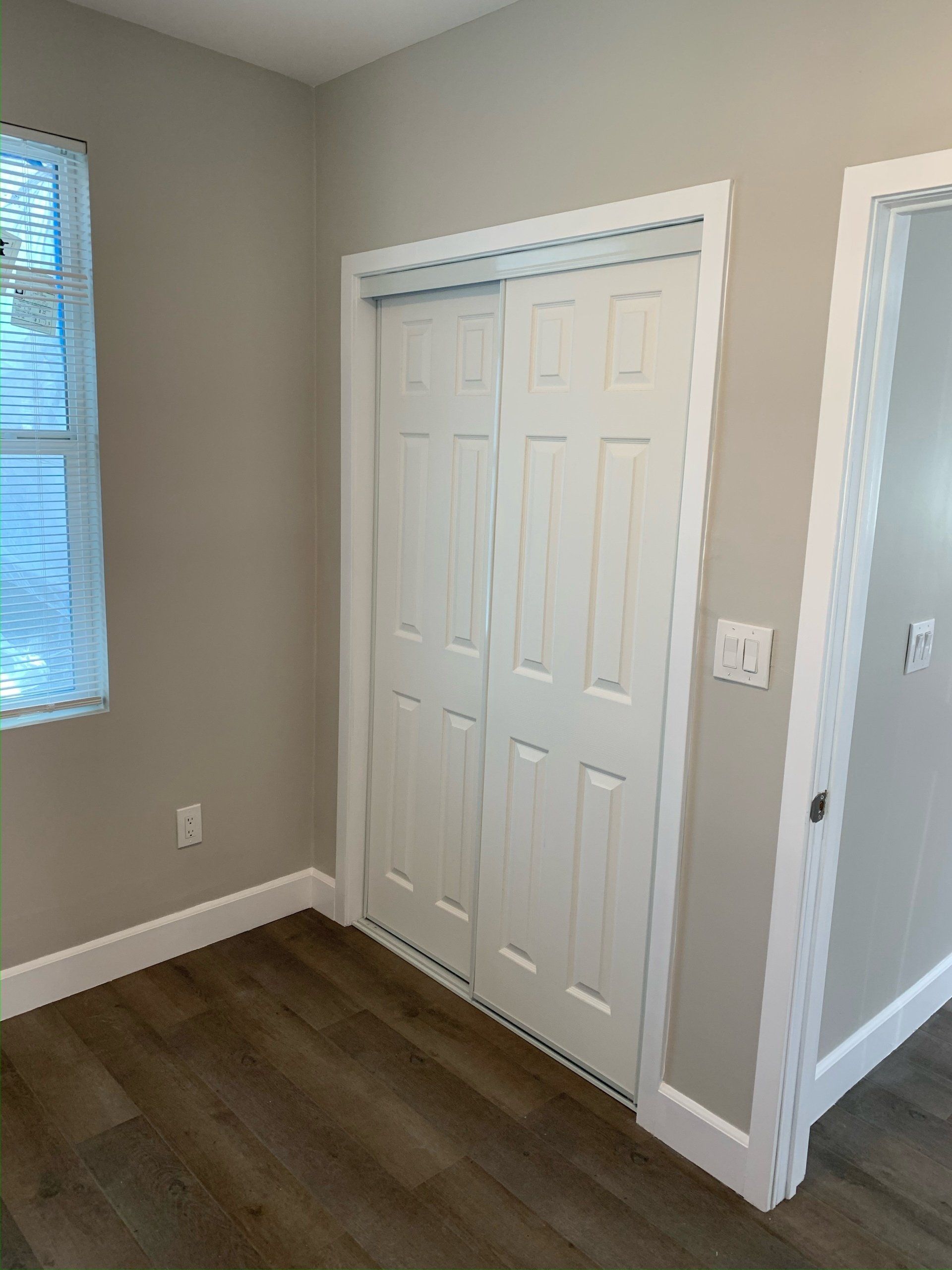 An empty room with a closet and a window.