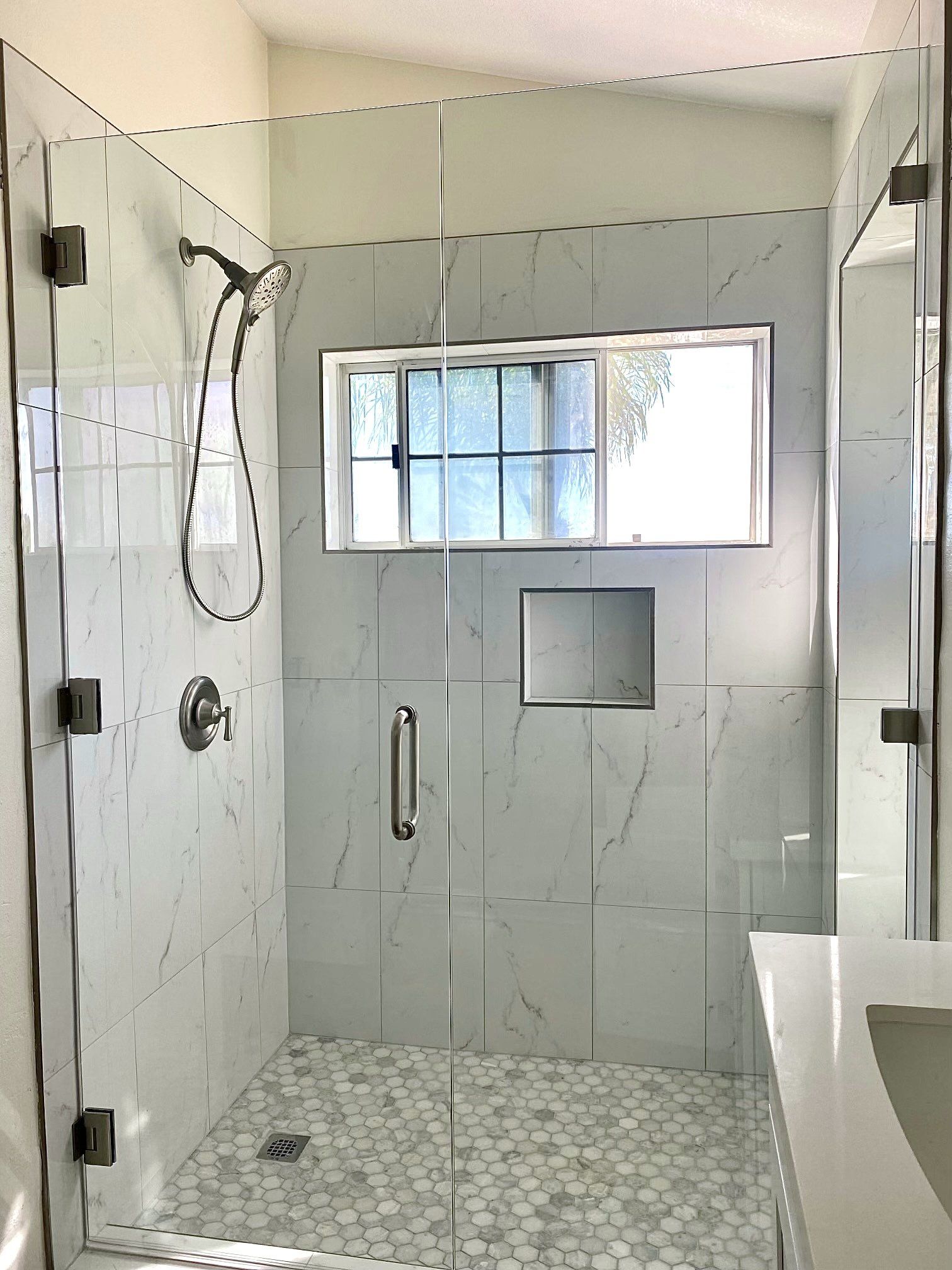 A bathroom with a walk in shower and a window.