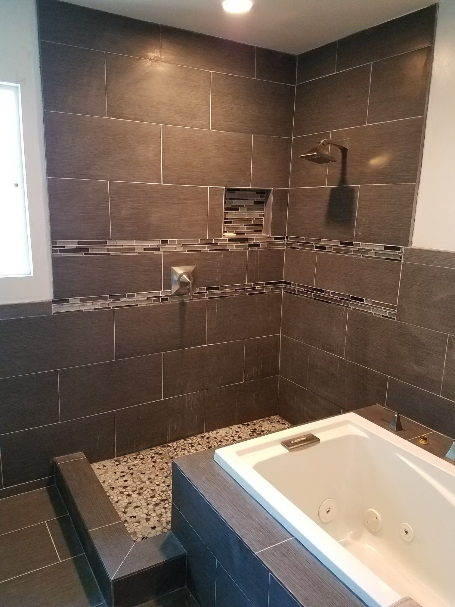 A bathroom with a tub , shower , and tiled walls.