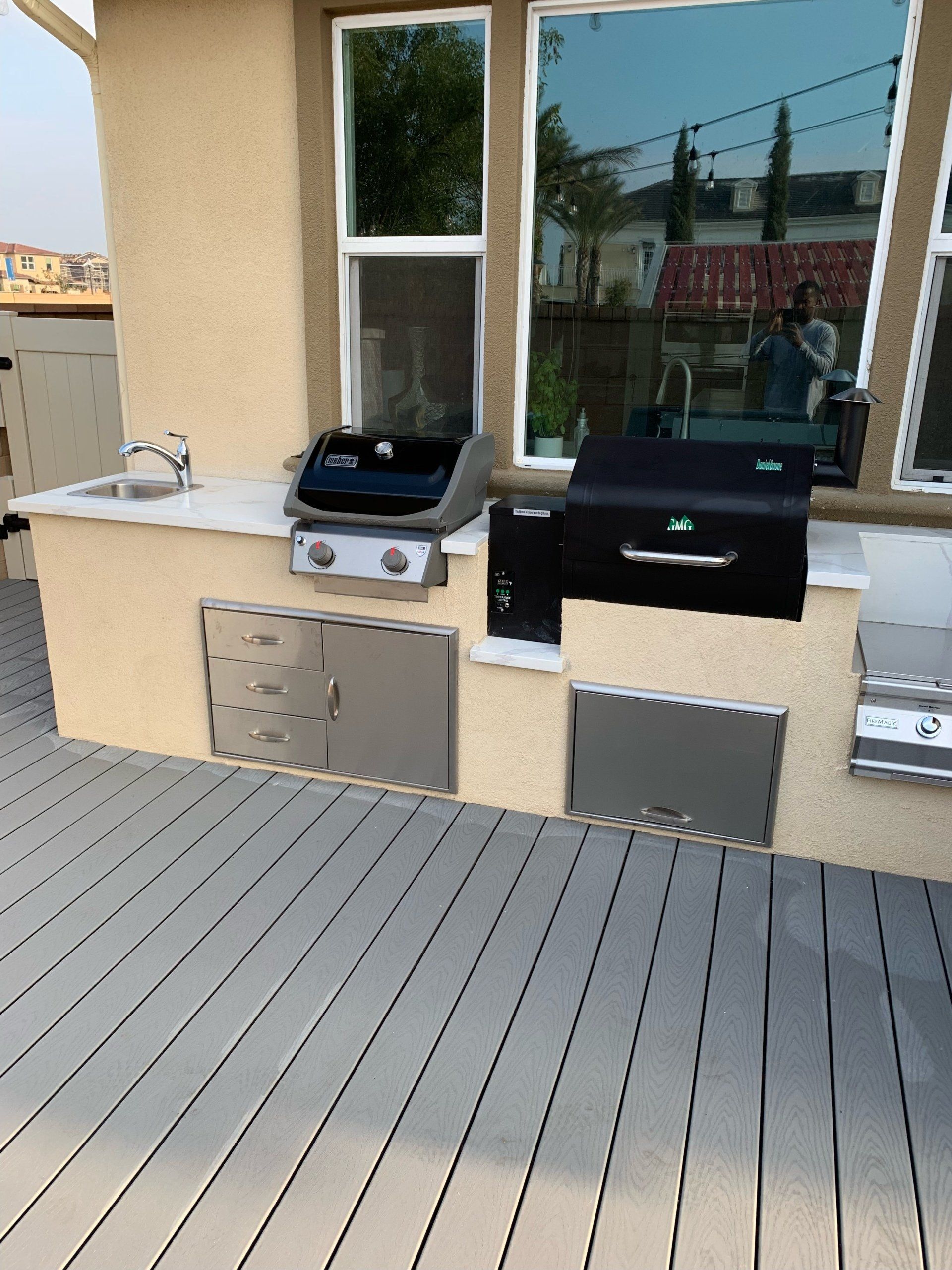 An outdoor kitchen with a grill and sink on a deck
