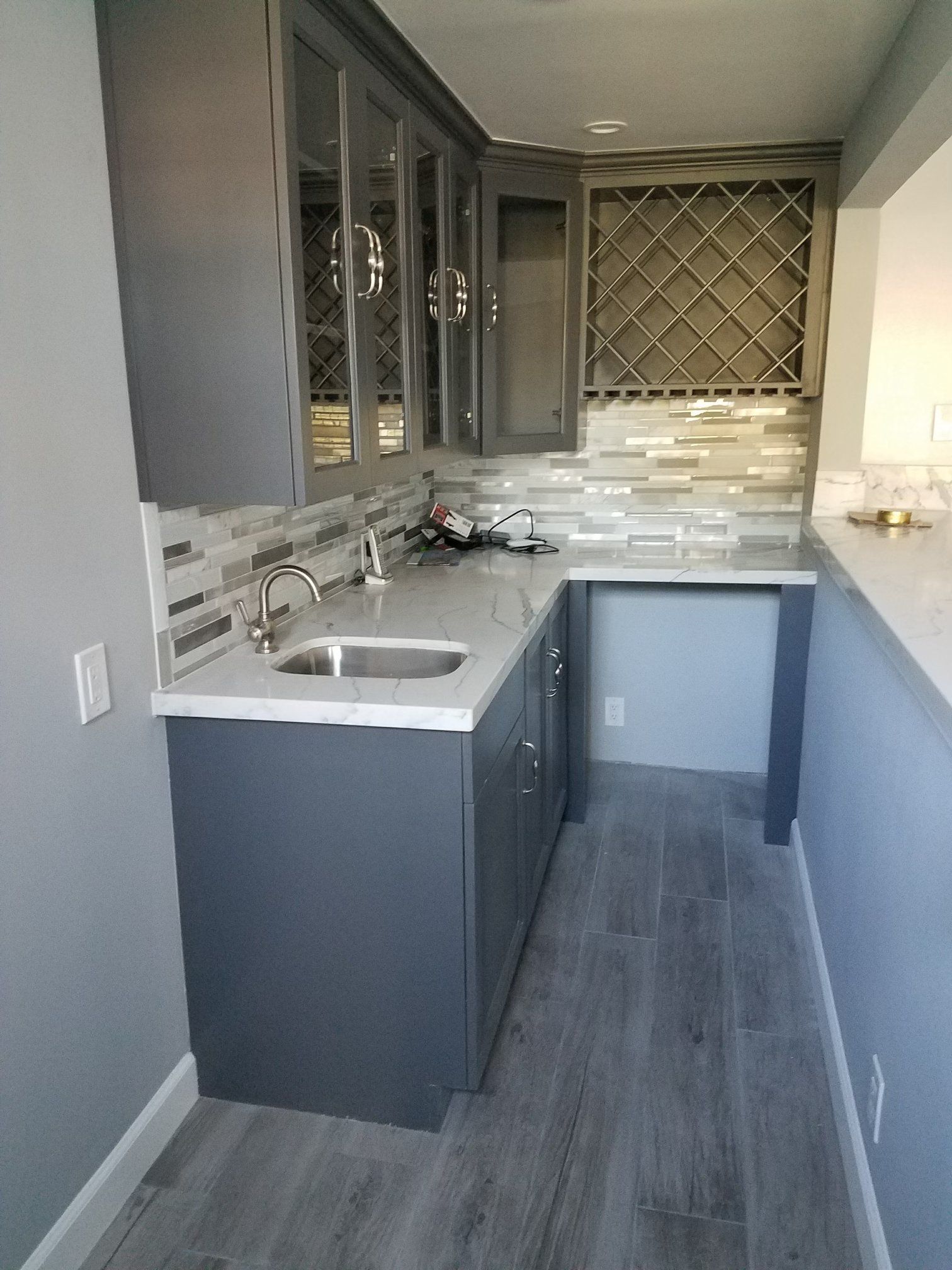 A kitchen with a sink , cabinets , and a wine rack.