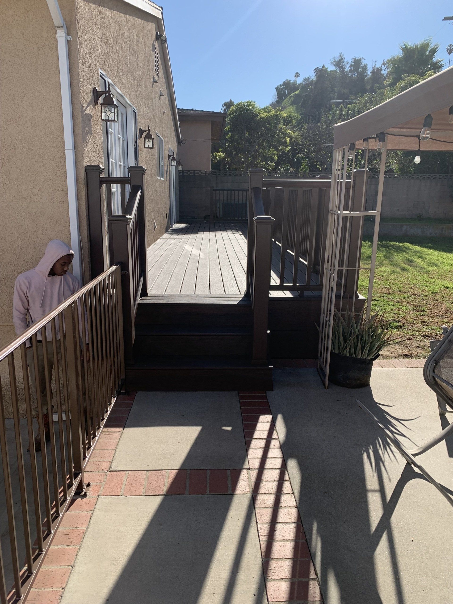 A person is standing in front of a house with a wooden deck.