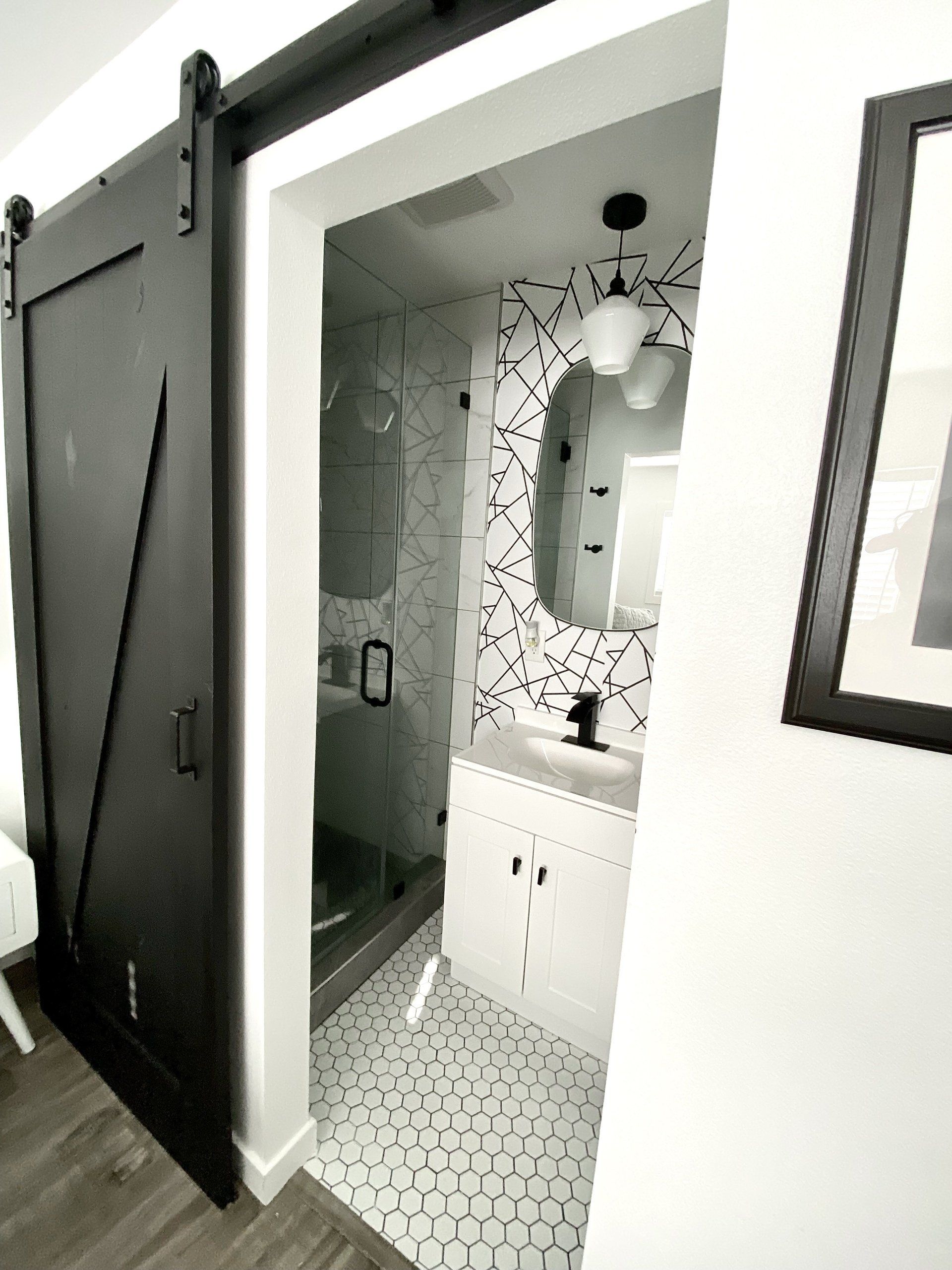 A bathroom with a sliding barn door and a sink.