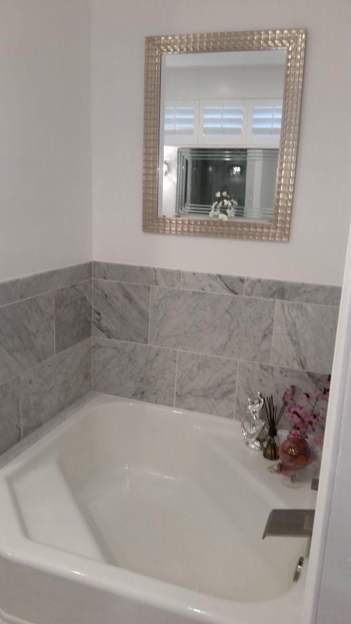 A bathroom with a bathtub and a mirror on the wall.