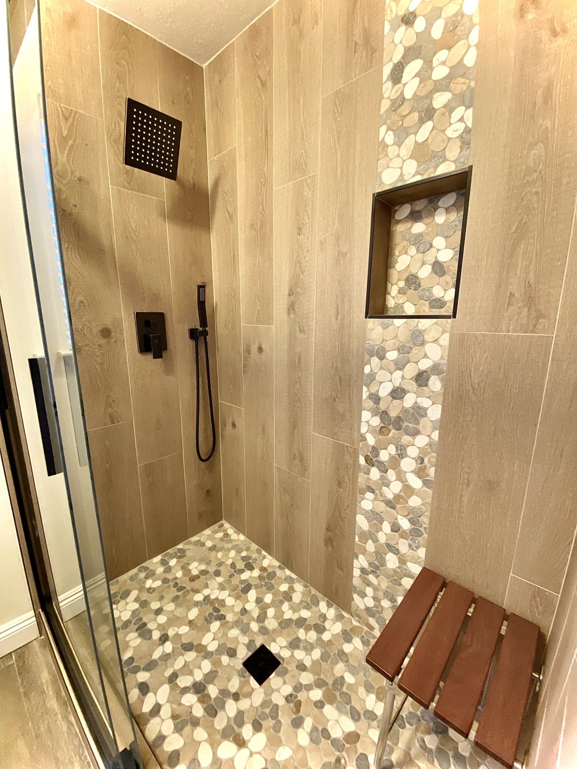 A bathroom with a walk in shower and a wooden bench.