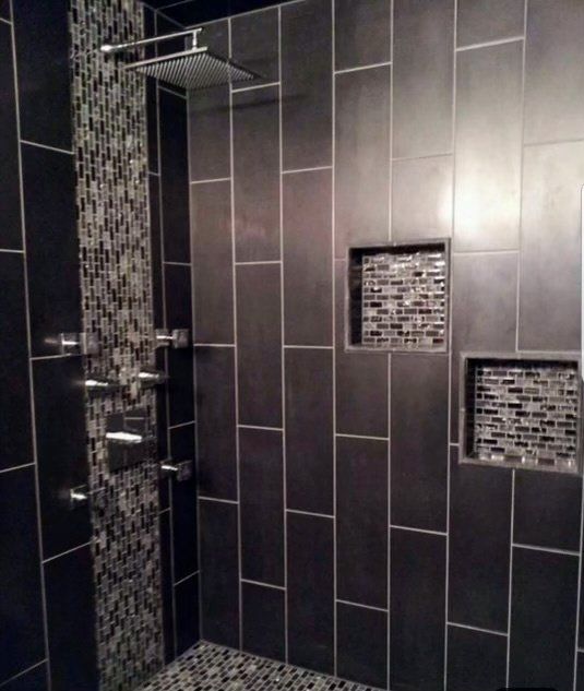 A bathroom with black tiles and a shower head