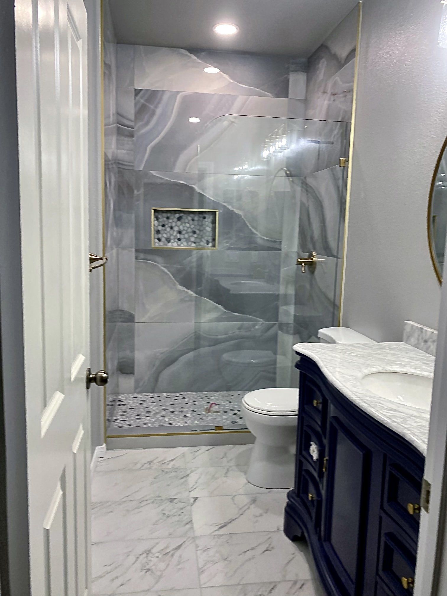 A bathroom with a walk in shower , toilet , sink and mirror.