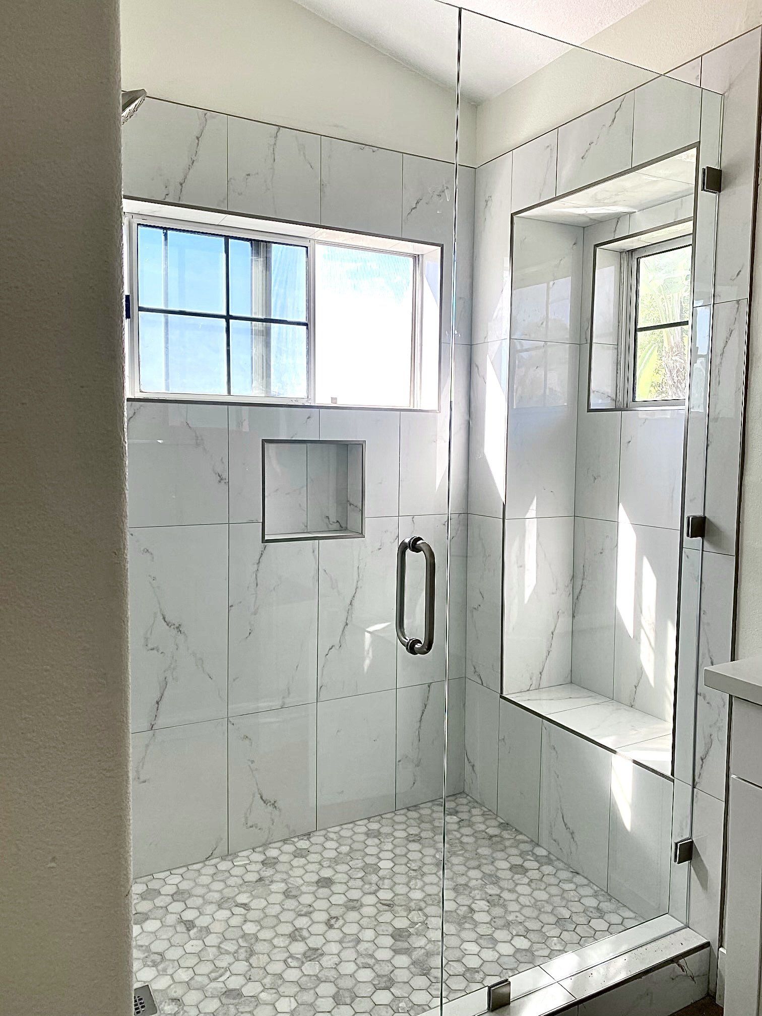 A bathroom with a walk in shower and a window.