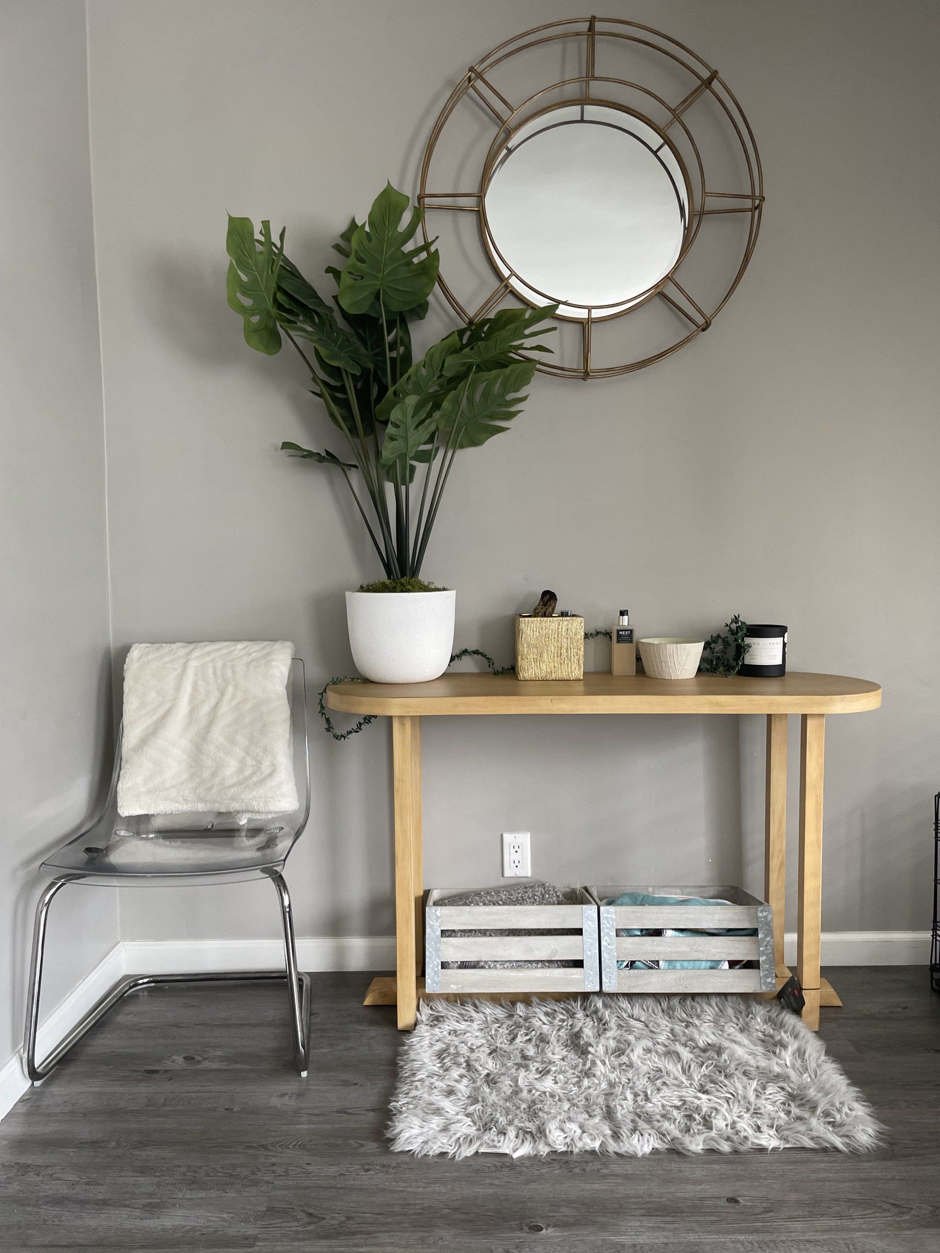 There is a table with a plant on it and a mirror on the wall.