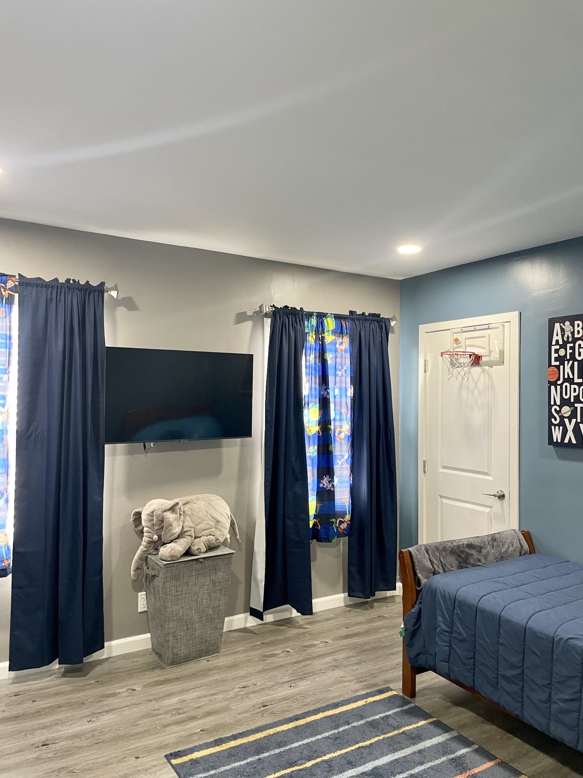 A bedroom with a bed , television , and blue curtains.
