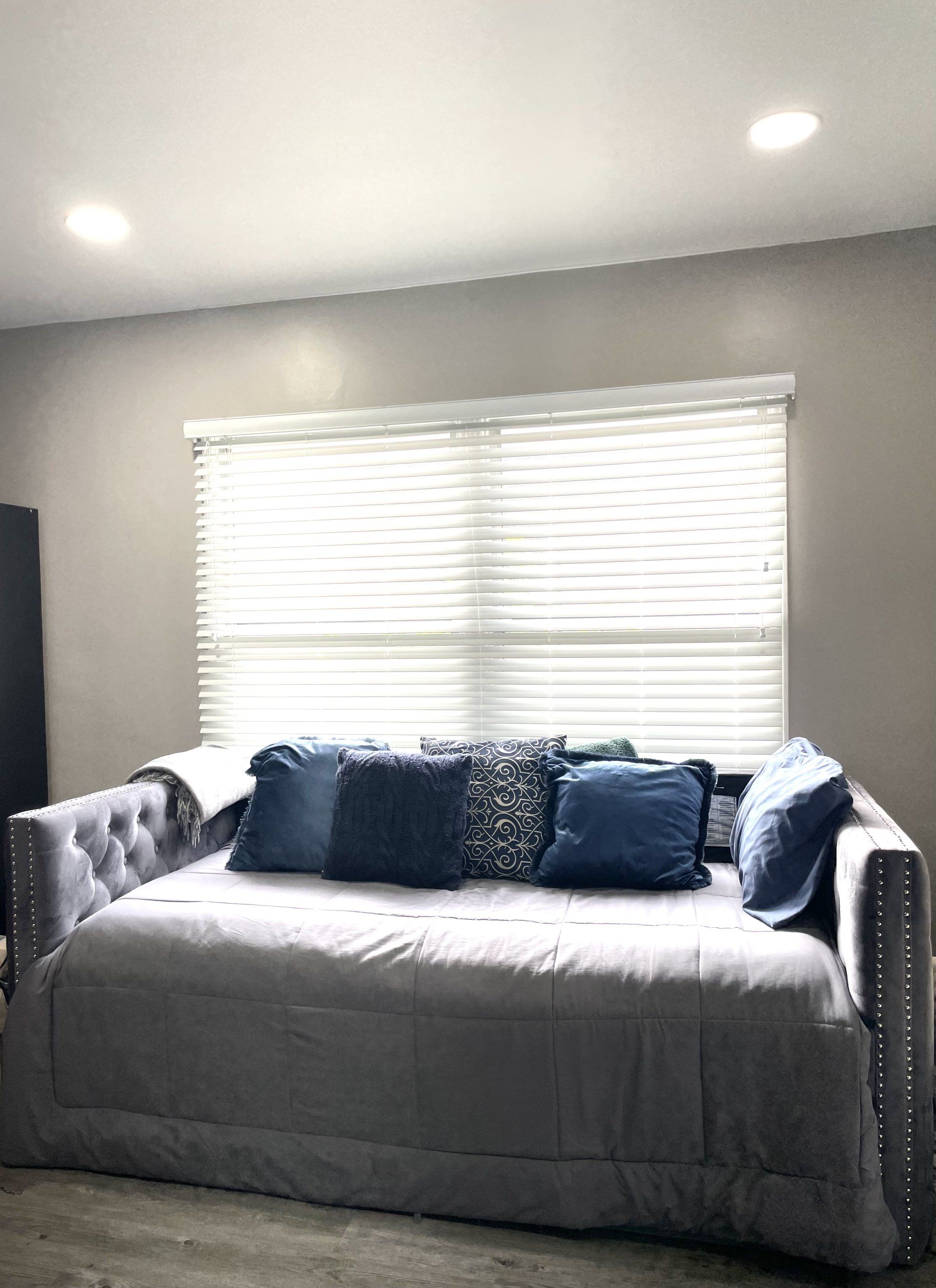 A day bed is sitting in front of a window in a living room.