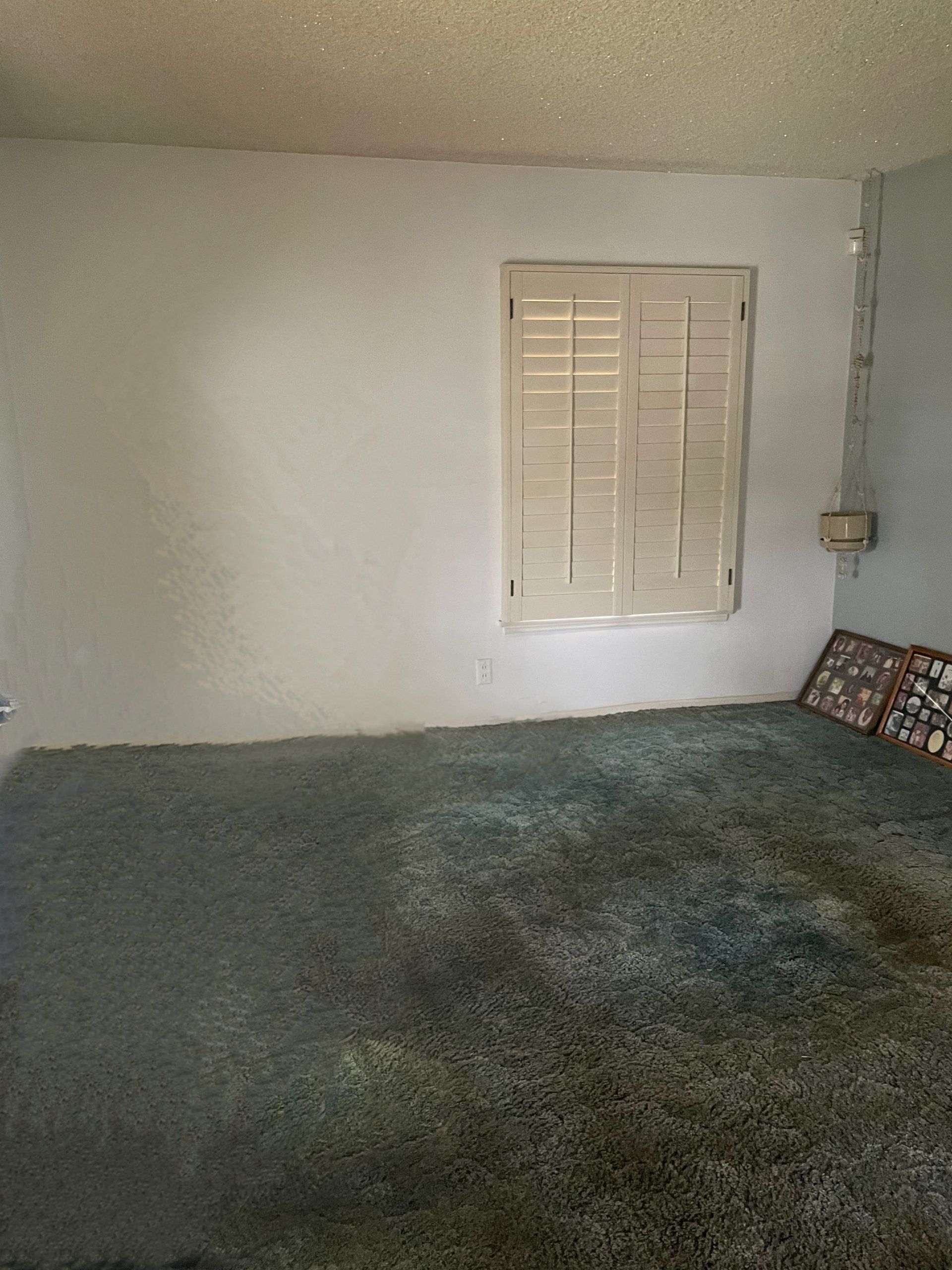 A bedroom with a bed and a window with shutters.