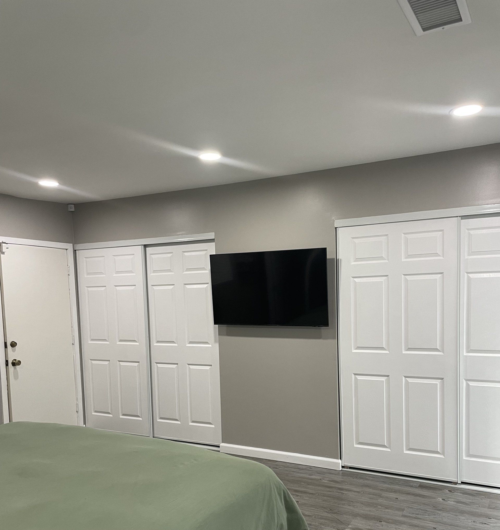 A bedroom with a bed and a flat screen tv on the wall