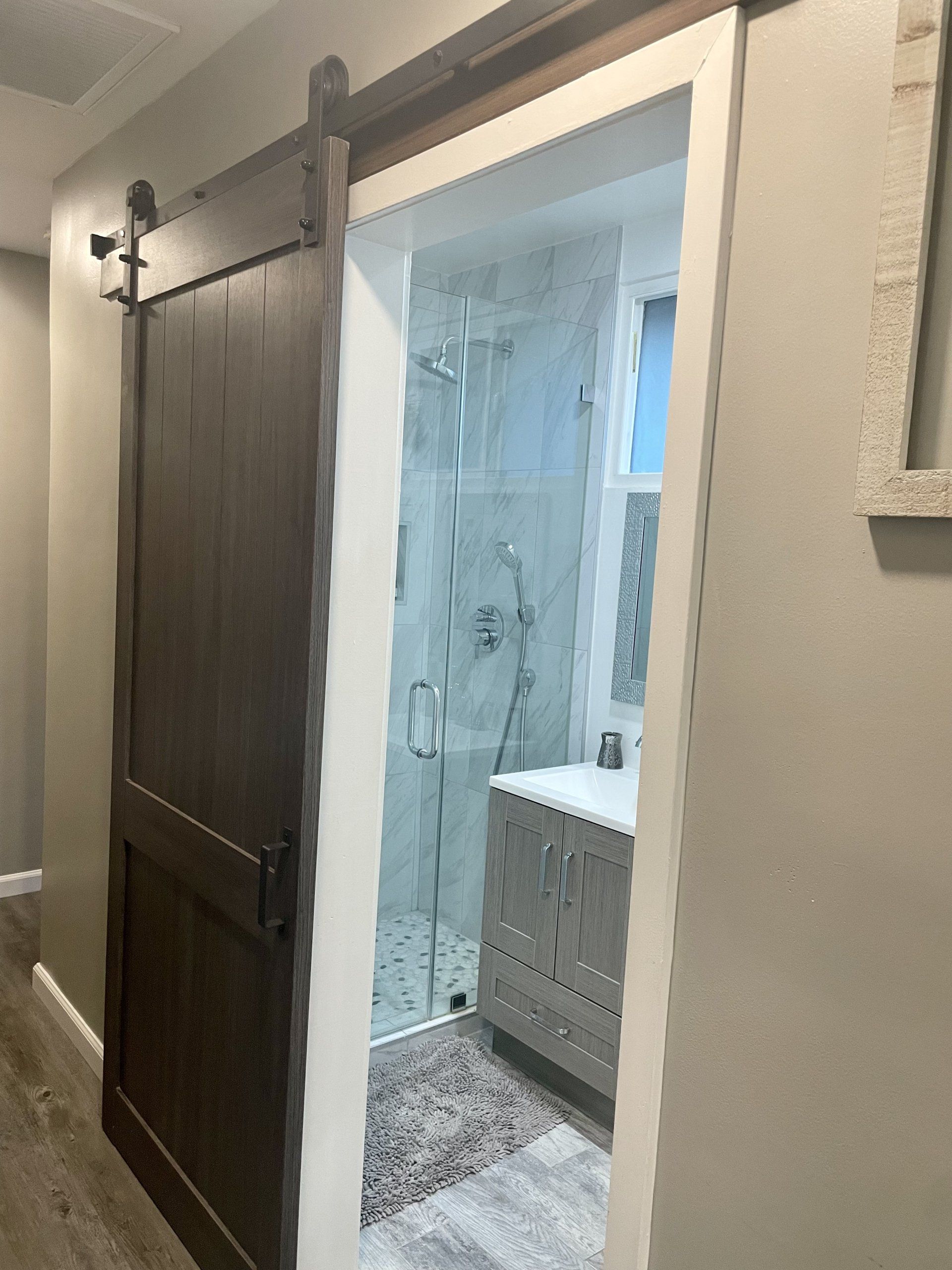 A bathroom with a sliding barn door leading to a shower.