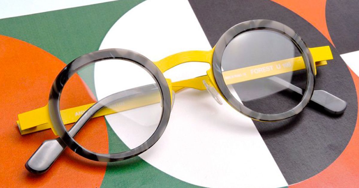 A pair of glasses with a yellow frame are sitting on a colorful surface