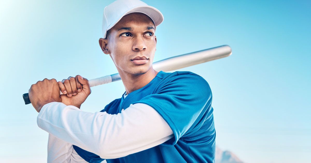 A man in a blue shirt and white hat is holding a baseball bat.