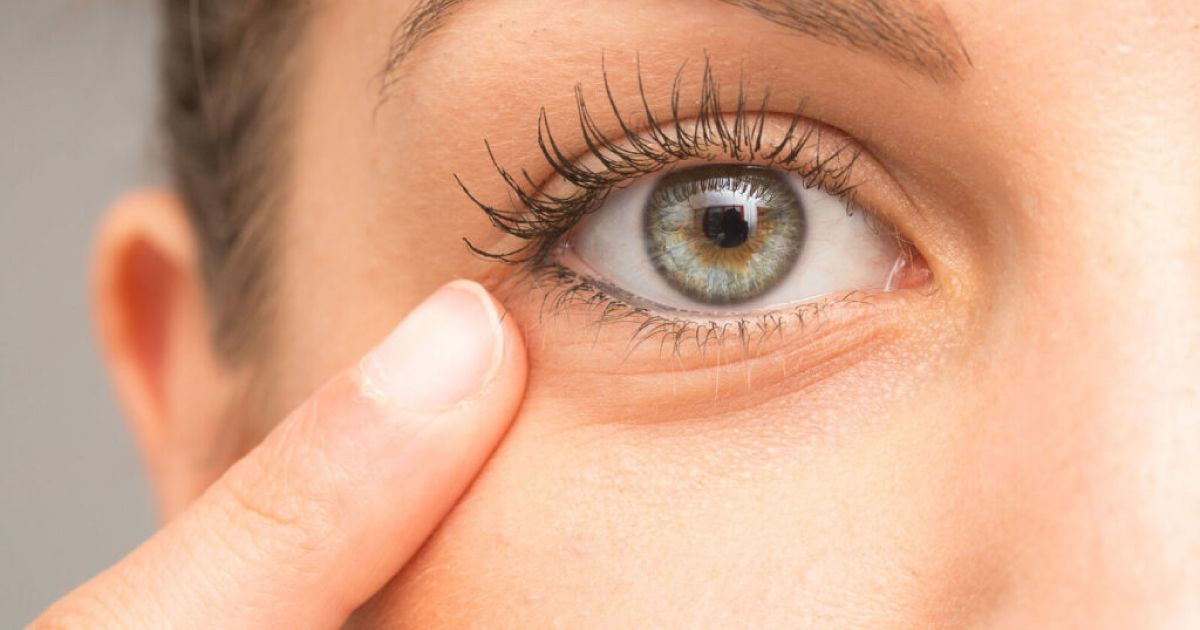 A close up of a woman 's eye with her finger pointing to it.