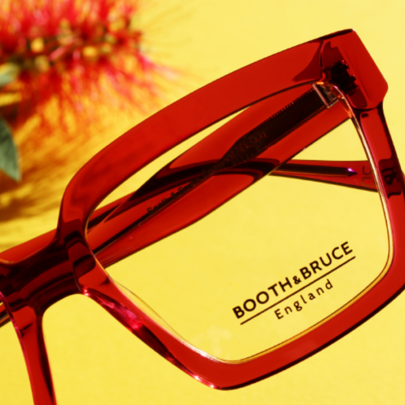 A pair of red booth & bruce glasses on a yellow background