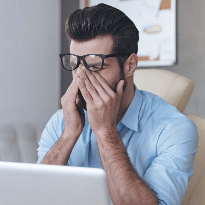 Man sitting at laptop computer rubbing his eyes