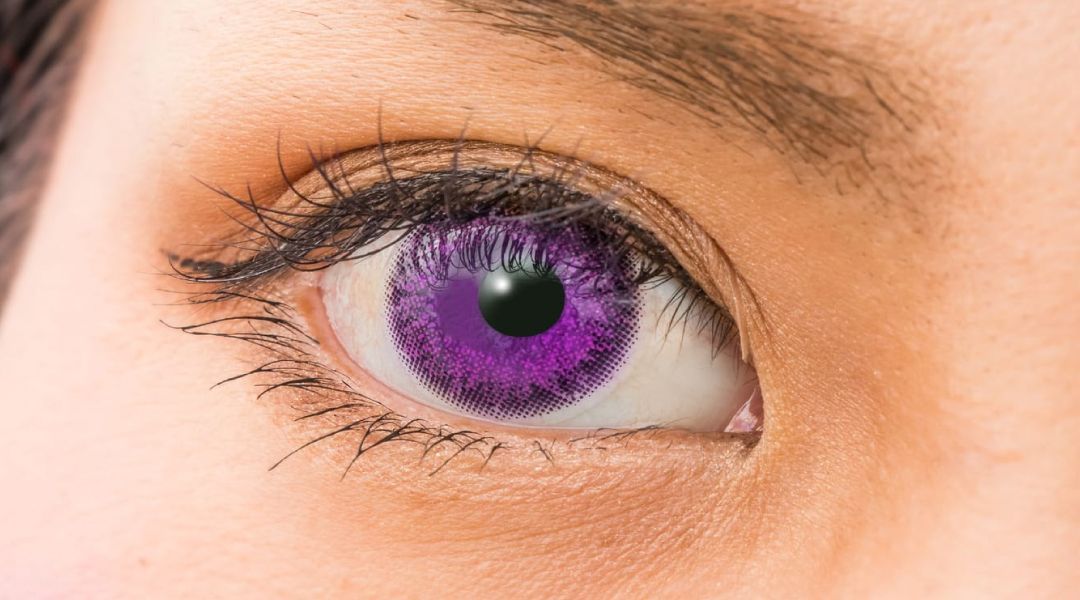 Close up of a woman's eye with purple colored contact lenses
