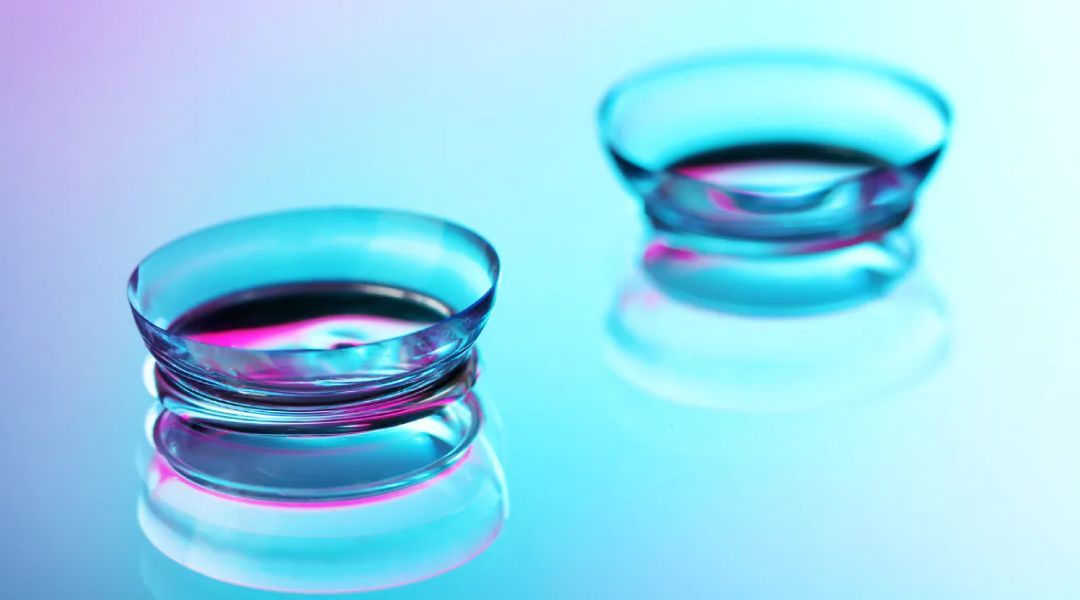 Two upside down contact lenses on a colored background