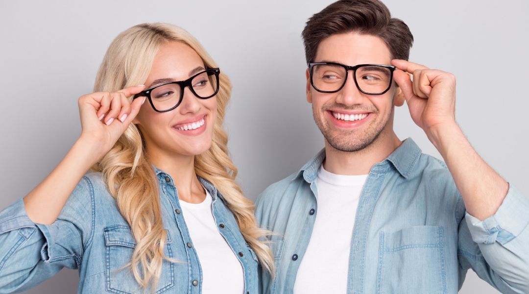 A man and a woman are wearing glasses and smiling .