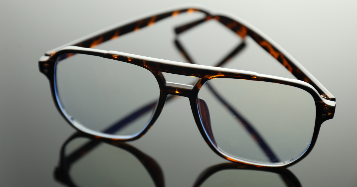 Tortoiseshell eyeglasses with a double bridge, resting on a reflective surface.