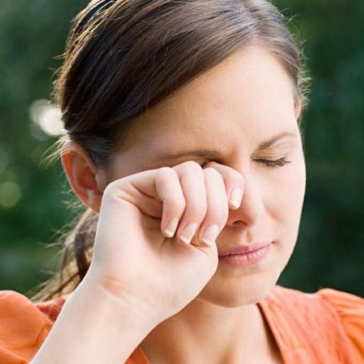 Woman standing outside rubbing her right eye