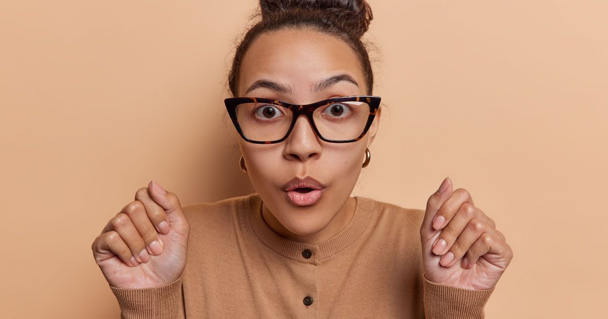 A woman wearing glasses is making a surprised face.