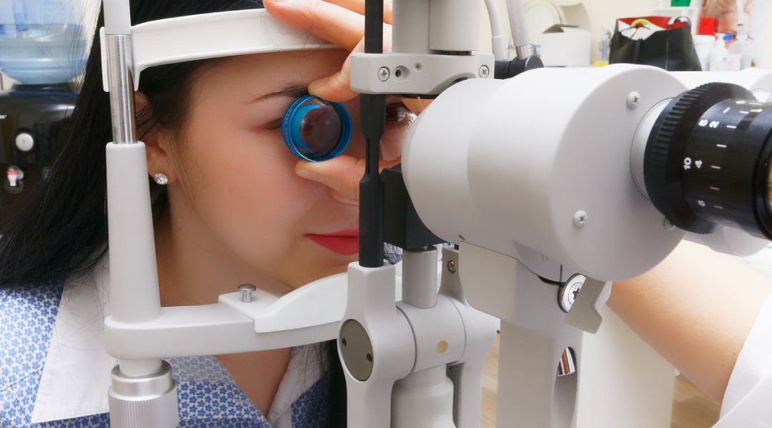 Woman with her head in a piece of equipment used to analyize the eyes during an exam