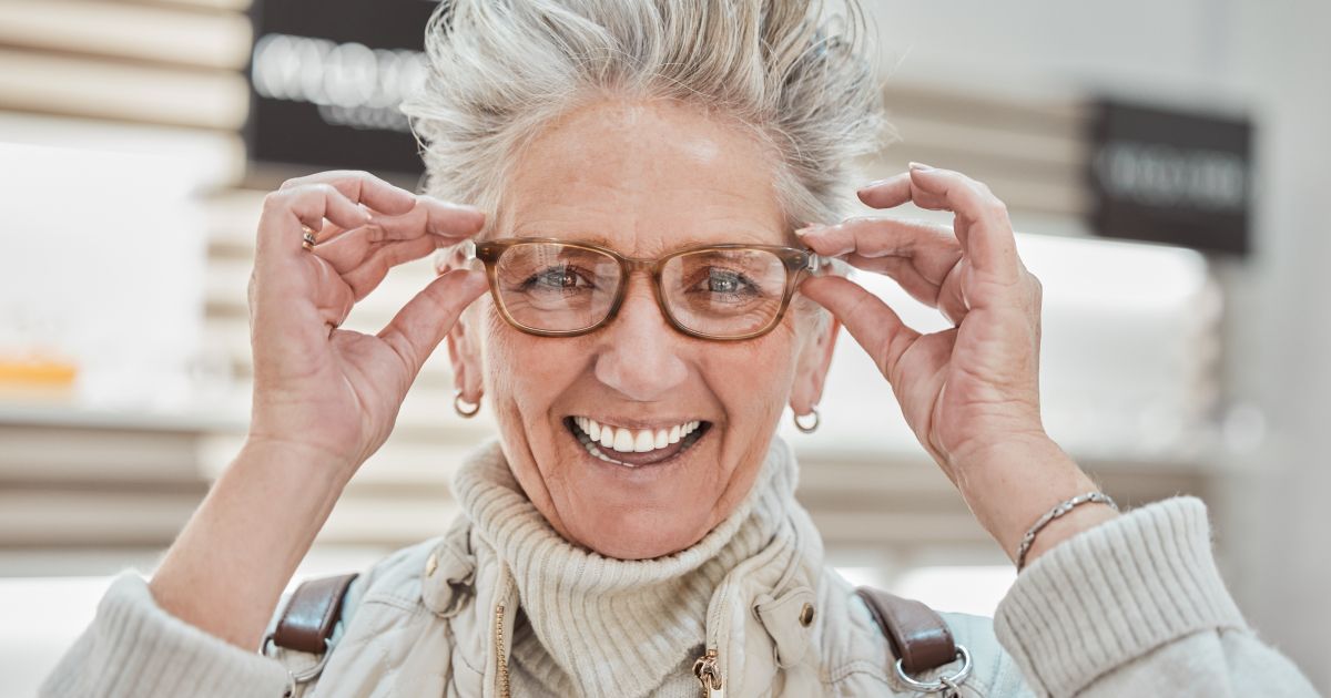 A senior woman wearing glasses and smiling.