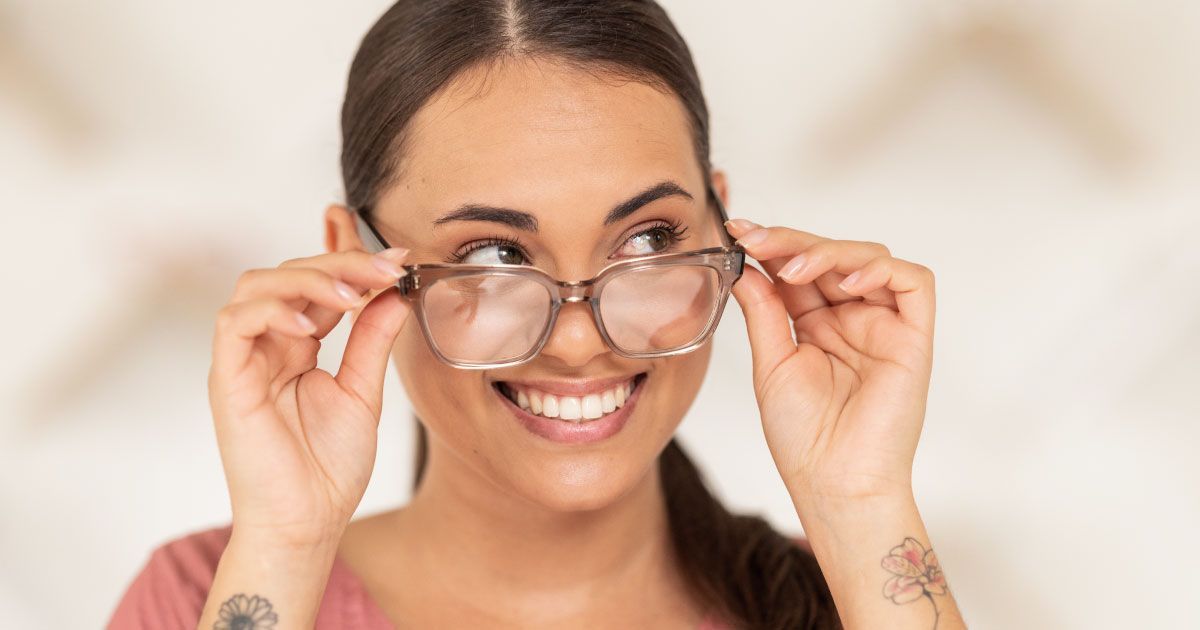 A woman is wearing large oversized glasses and smiling.