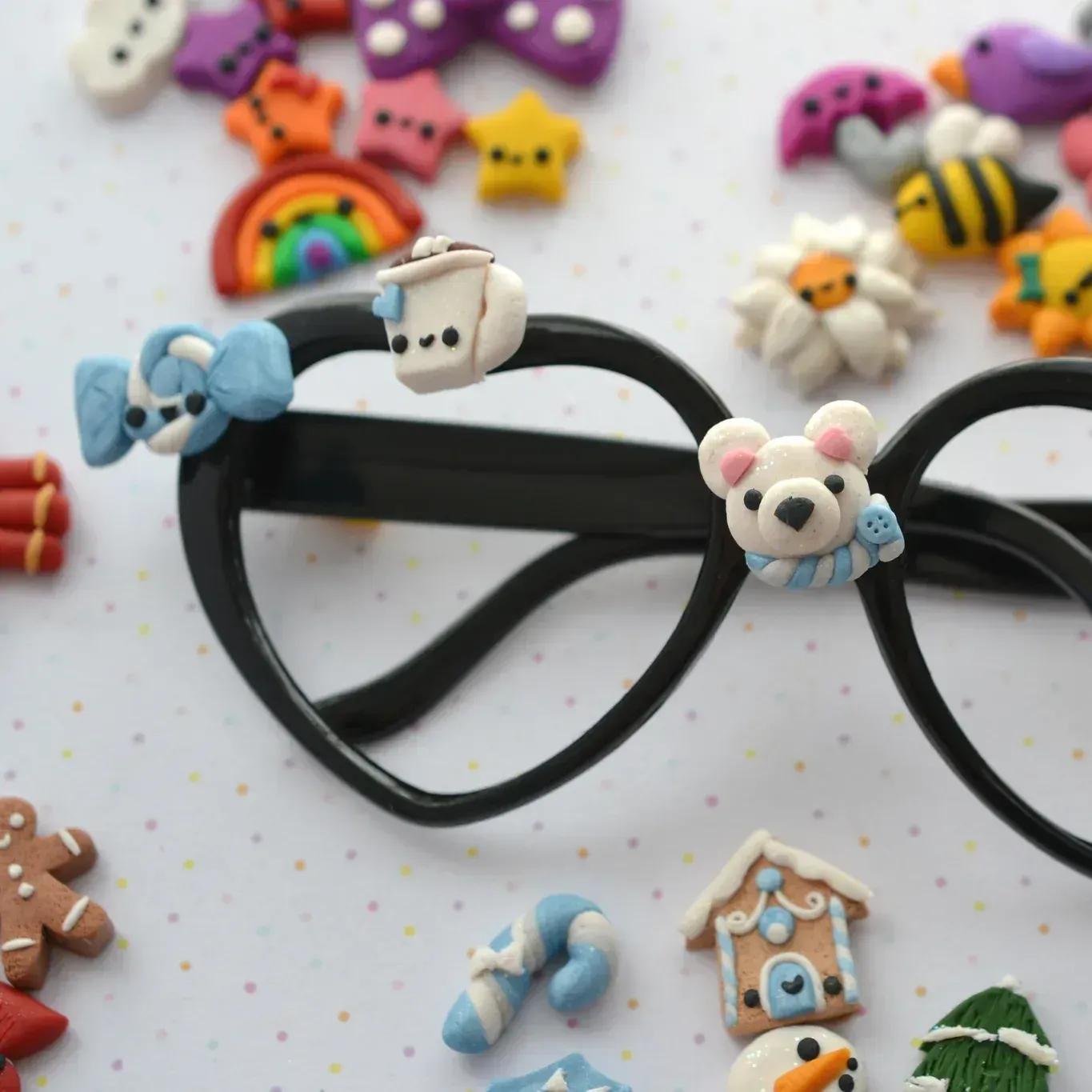 A pair of black youth glasses adorned and surrounded by small animal and holiday-themed eyewear charms.